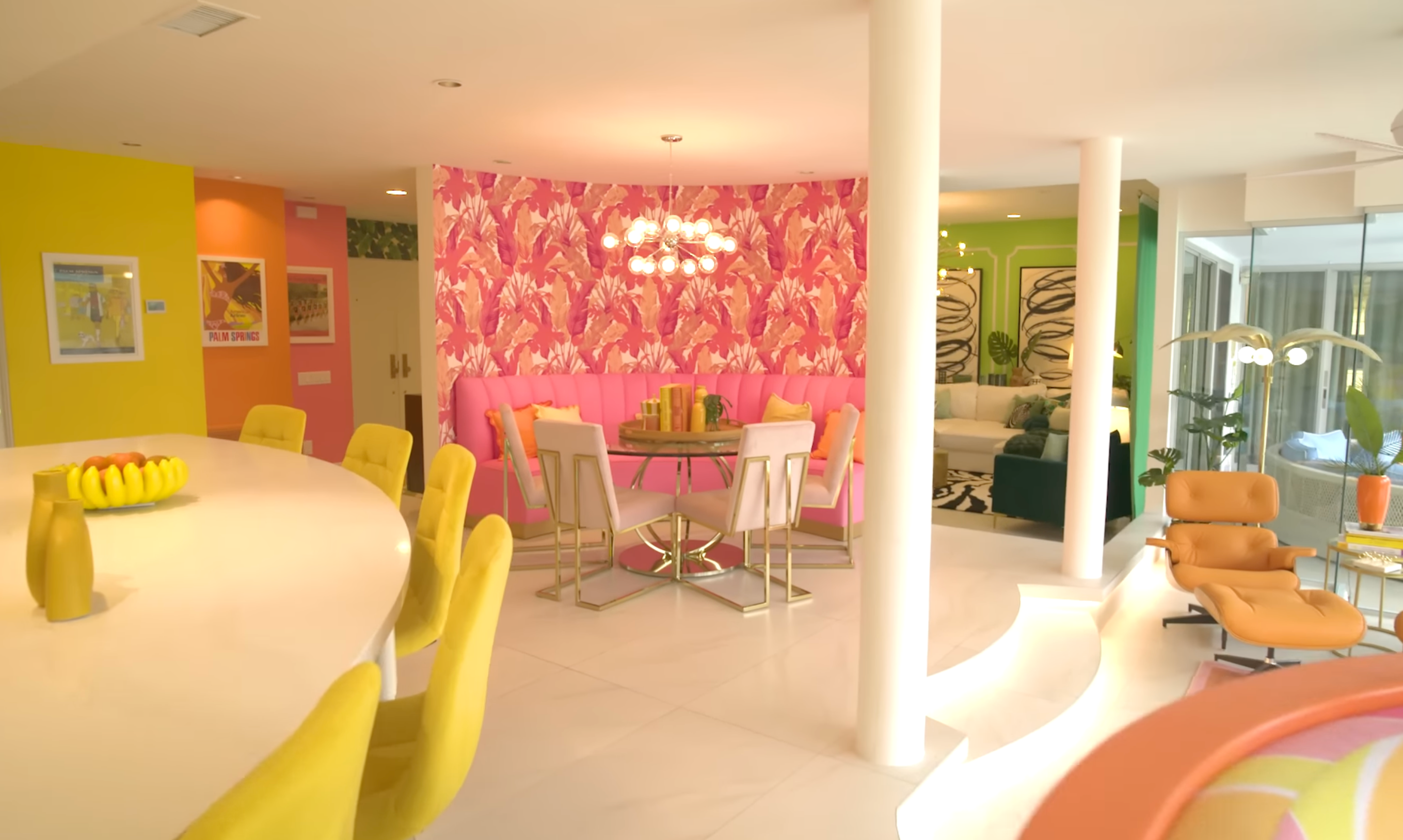 Stylish interior with retro furniture, colorful walls, and vibrant decor, featuring a circular eating array with pinkish seating and modern lighting