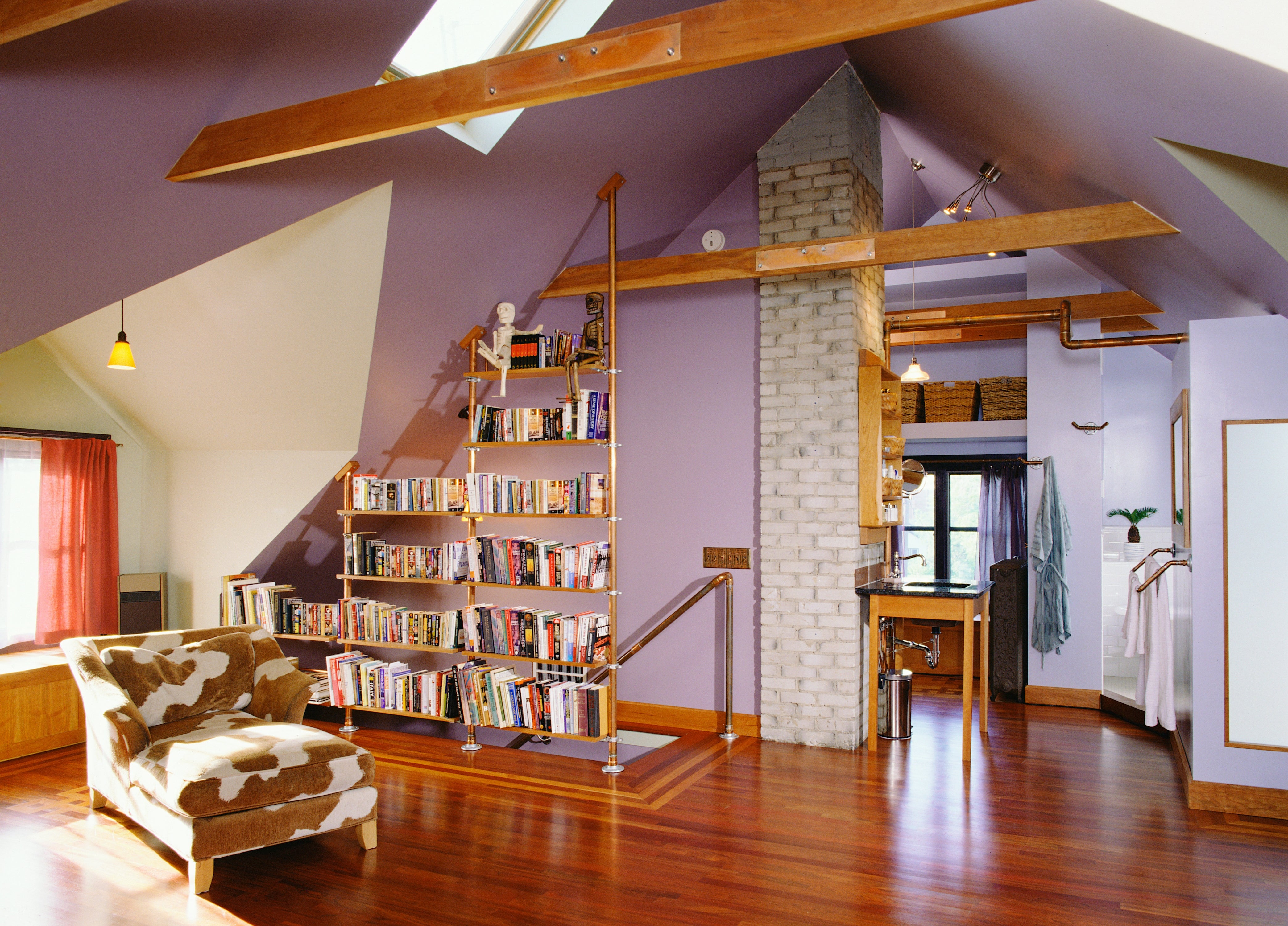 Spacious attic with woody beams, books connected built-in shelves, a cowhide armchair, and a cozy speechmaking nook