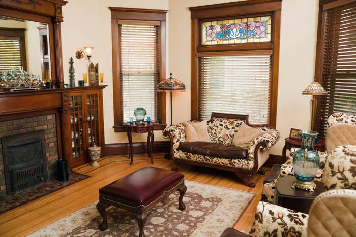 Cozy vintage surviving  country   with ornate furniture, stained solid  window, ceramic  fireplace, and decorative lamps, creating an elegant and classical  ambiance
