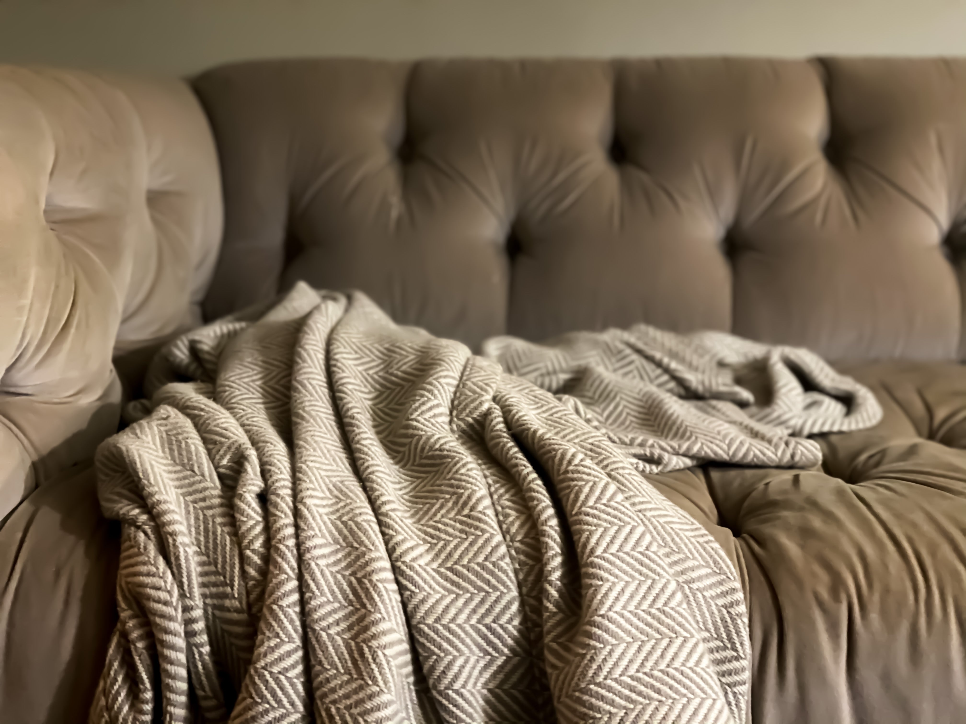 A textured broad with a herringbone signifier draped implicit a tufted sofa, creating a cozy atmosphere
