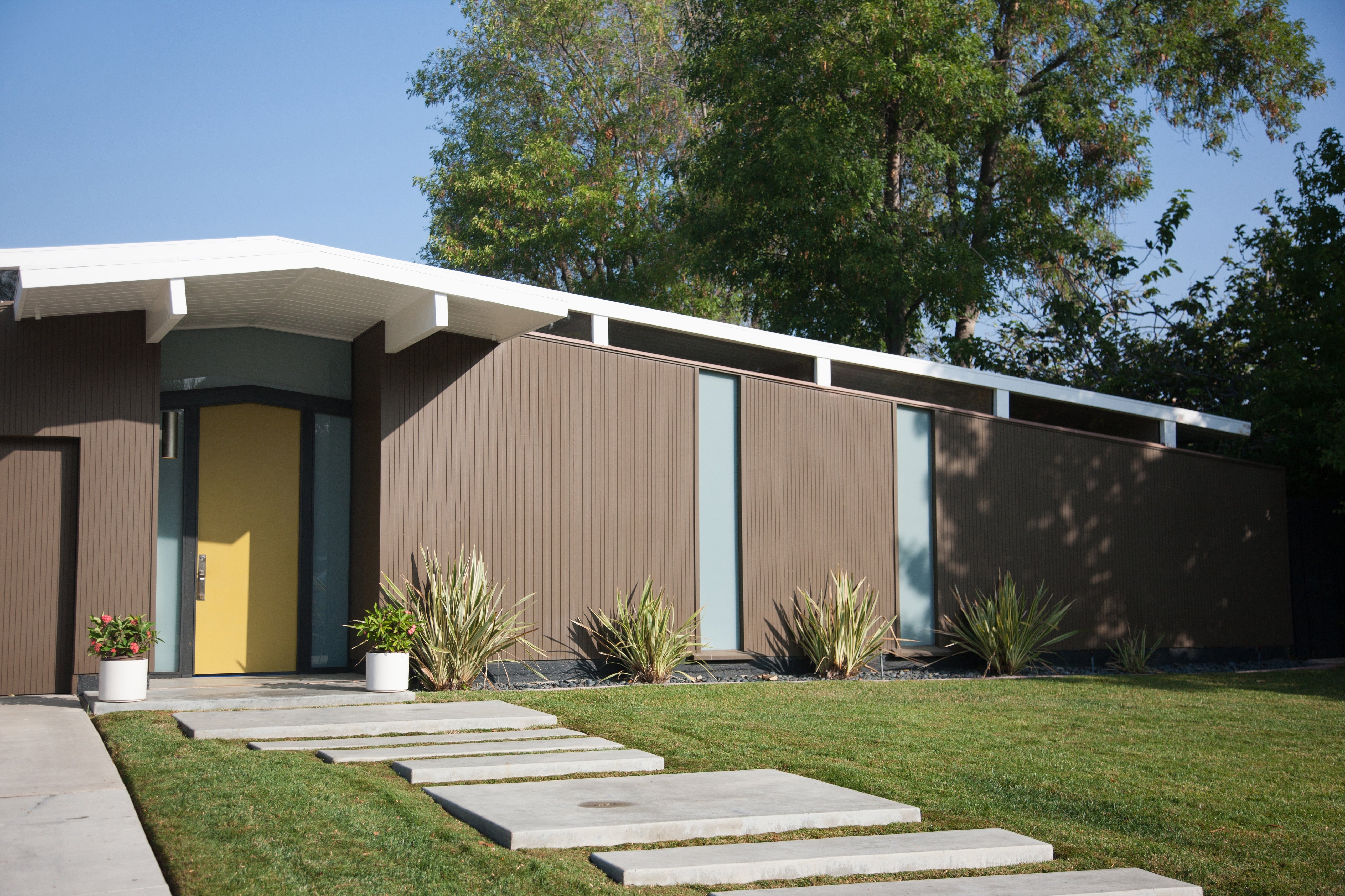 Mid-century modern location with geometric shapes, ample windows, and a level roof. Front gait features a manicured tract and stepping stones