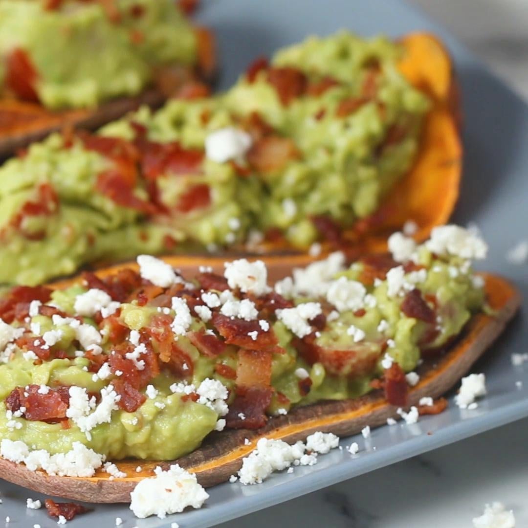 Sweet potato toast topped with guacamole, bacon crumbles, and crumbled white cheese on a plate