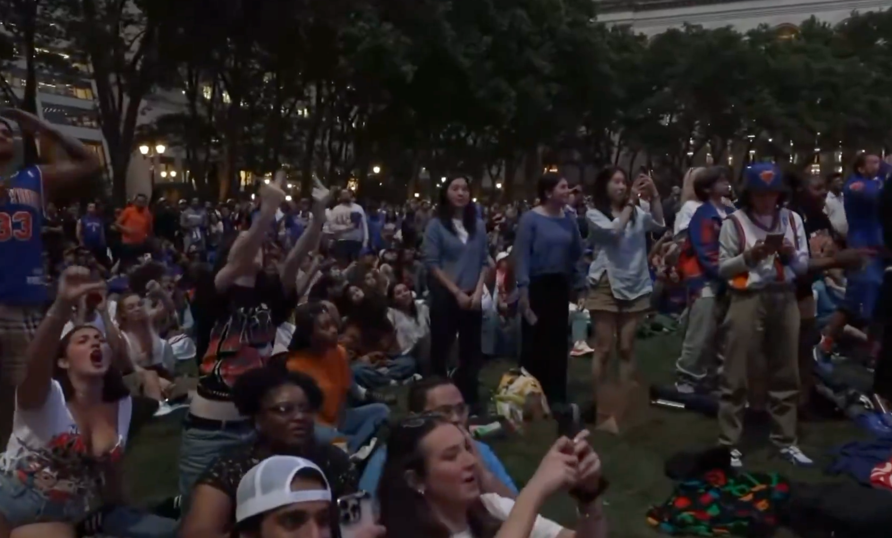 A ample assemblage gathered outdoors, sitting and standing, watching an lawsuit with excitement and cheering
