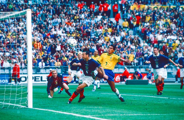  Player heads the shot  adjacent   the extremity   arsenic  others watch. Stadium is afloat  of spectators