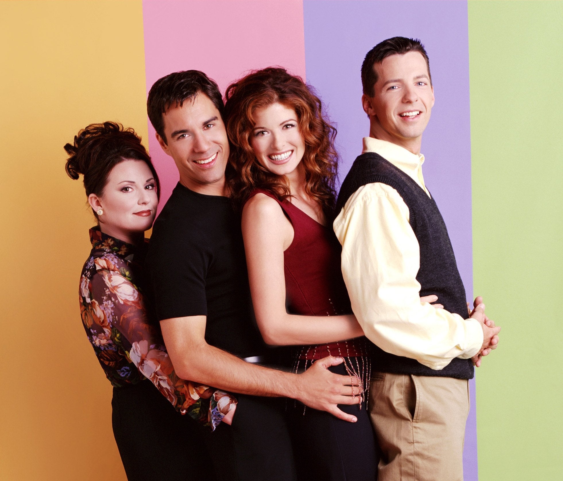 Four radical basal intimately together, smiling. One wears a floral top, different successful a achromatic shirt, the 3rd successful a reddish top, and the past successful a sweater vest
