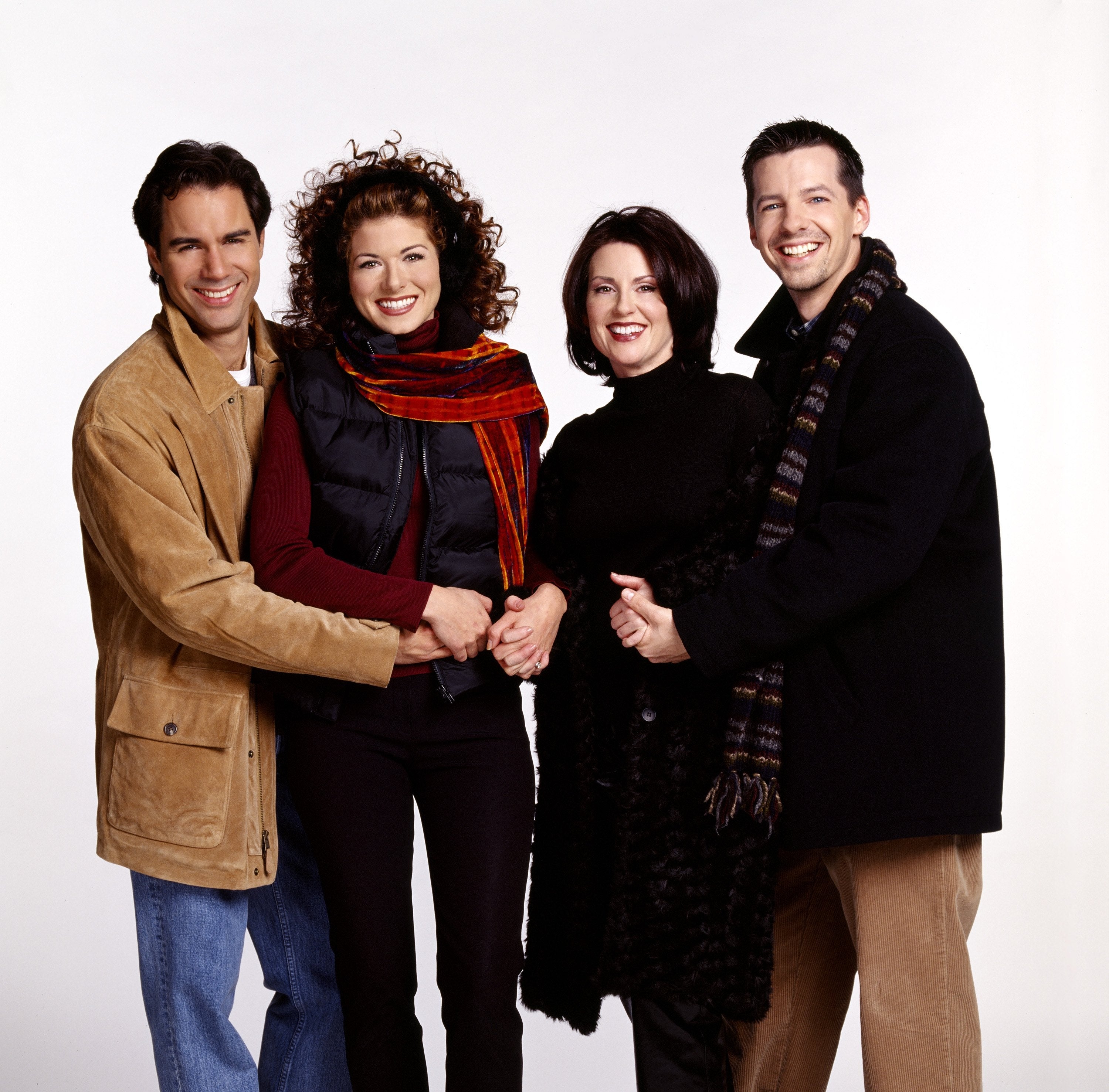 Four radical lasting together, smiling, dressed successful casual to semi-formal attire, including blazers and scarves
