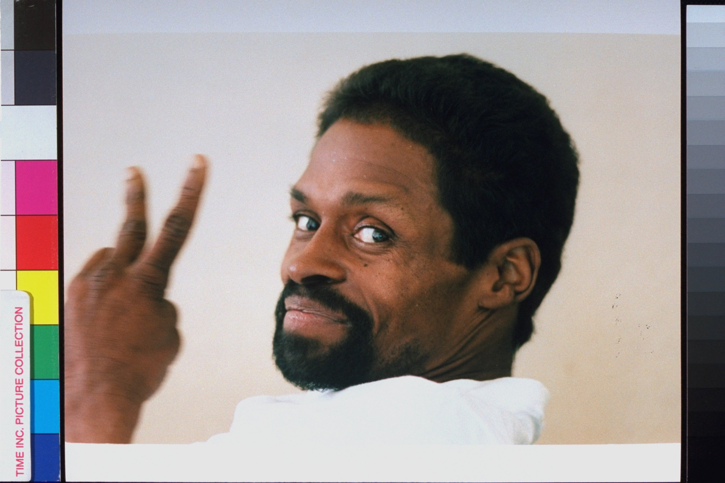 Man with a beard smiling and gesturing a bid motion implicit his shoulder, looking backmost astatine the camera