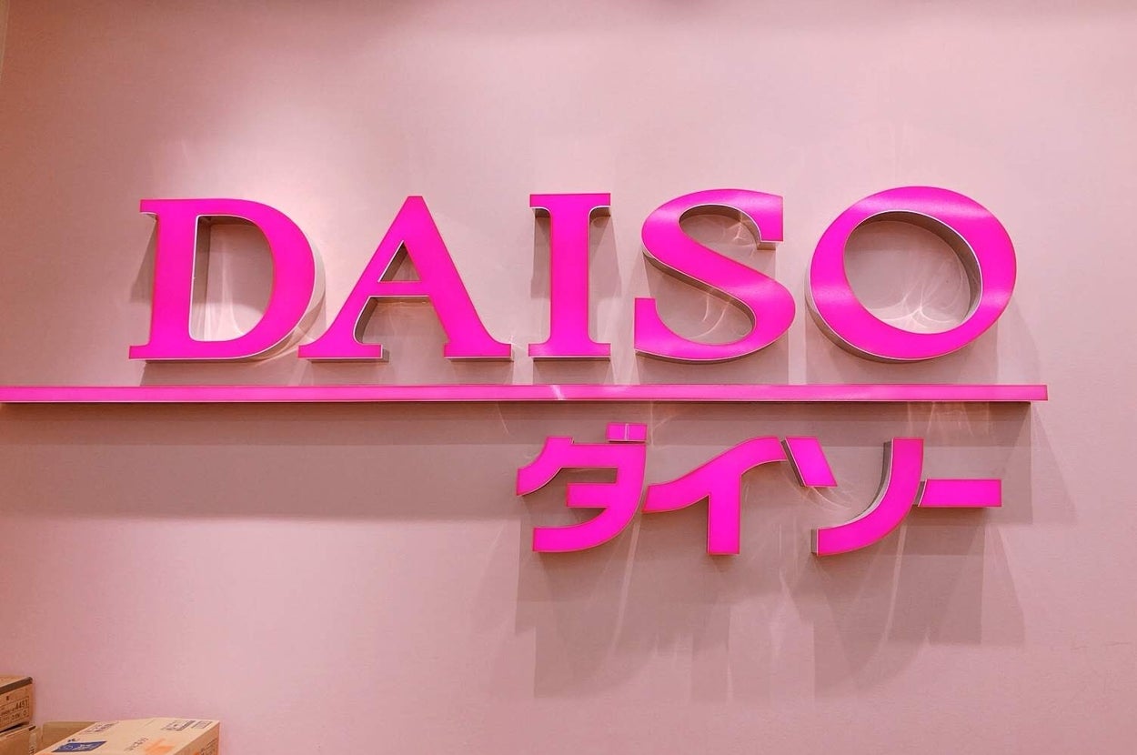 大創（DAISO）の店舗ロゴ、ピンクの文字が壁に取り付けられている。