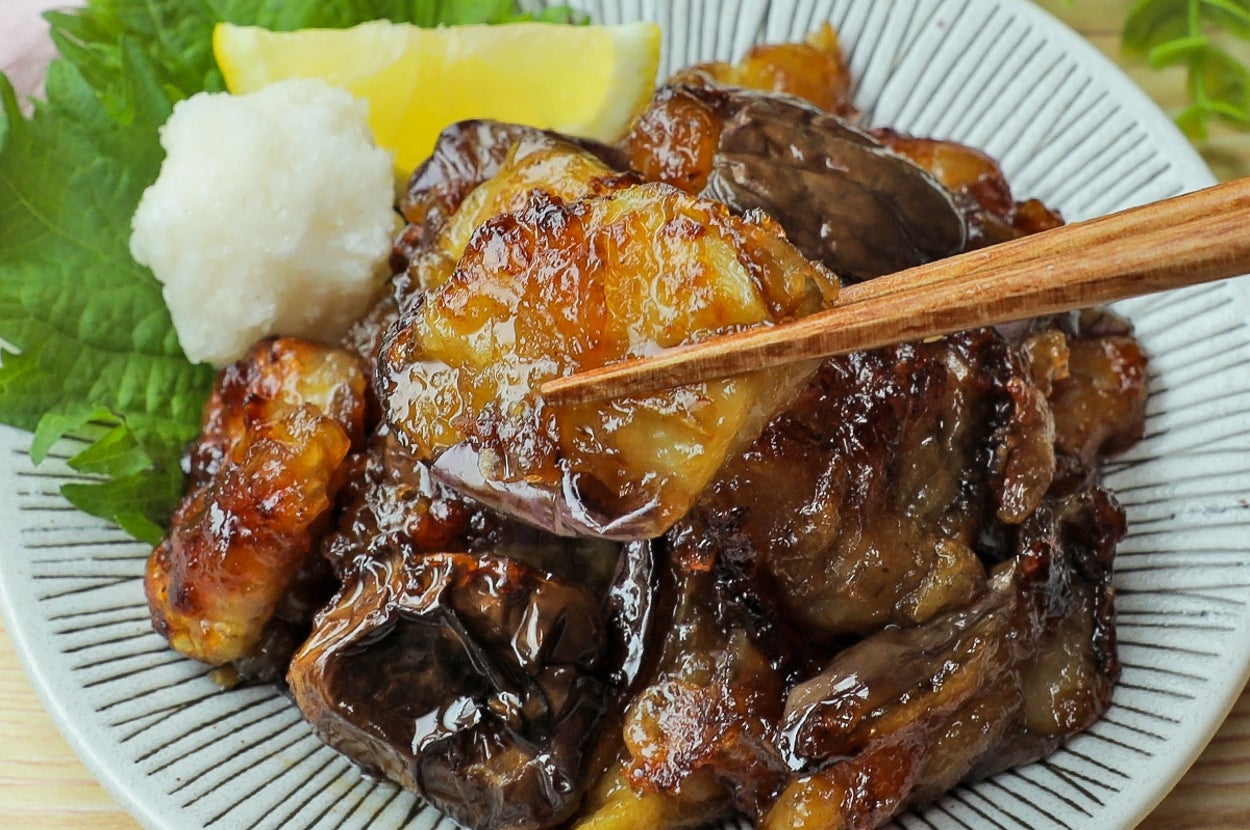 焼き茄子と焼き肉が皿に盛られ、薬味とレモンが添えられています。