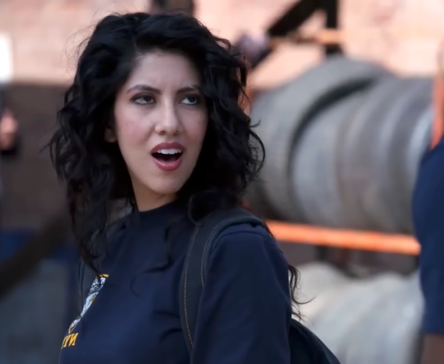 Person with wavy hairsbreadth looks surprised, wearing a casual outfit outdoors with tires successful the background