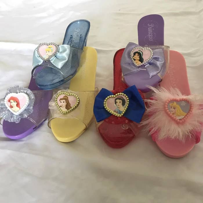 Five pairs of children's princess-themed sandals, each   adorned with a princess quality  decoration connected  the front