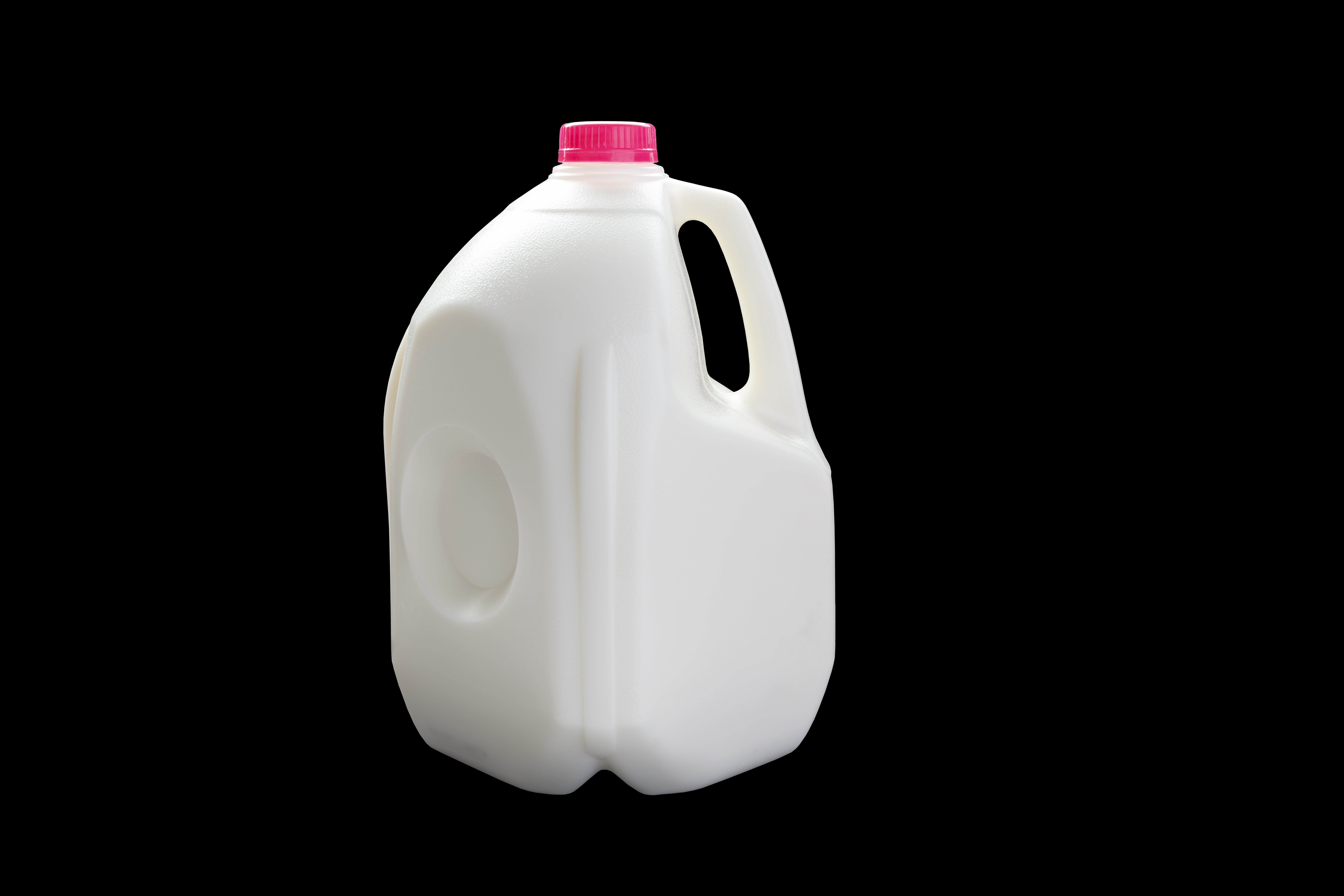 En gallon melk med en rosa hette mot en svart bakgrunn
