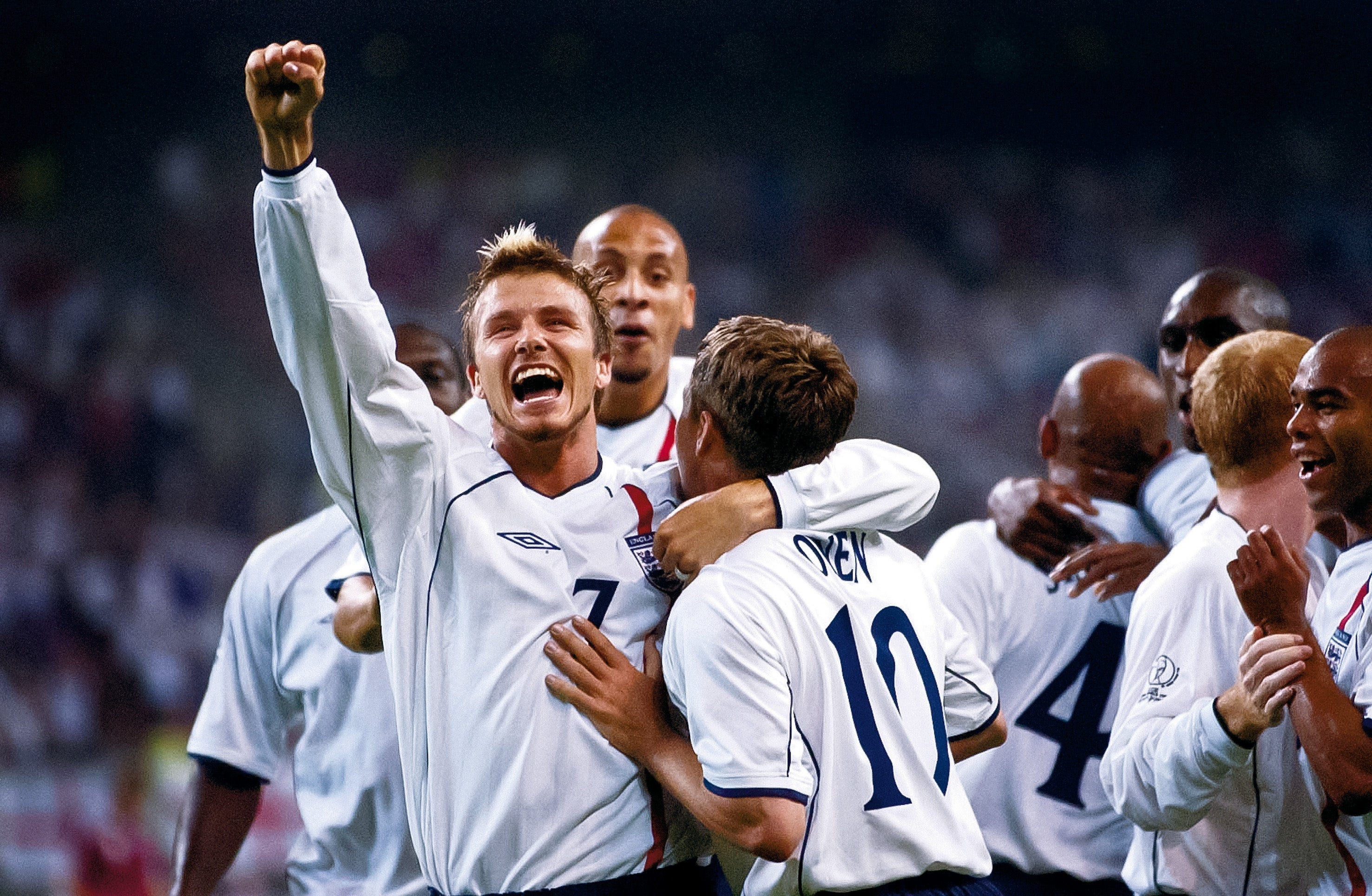 Soccer players celebrating connected the field, 1 with an limb raised triumphantly, wearing jerseys with disposable squad numbers