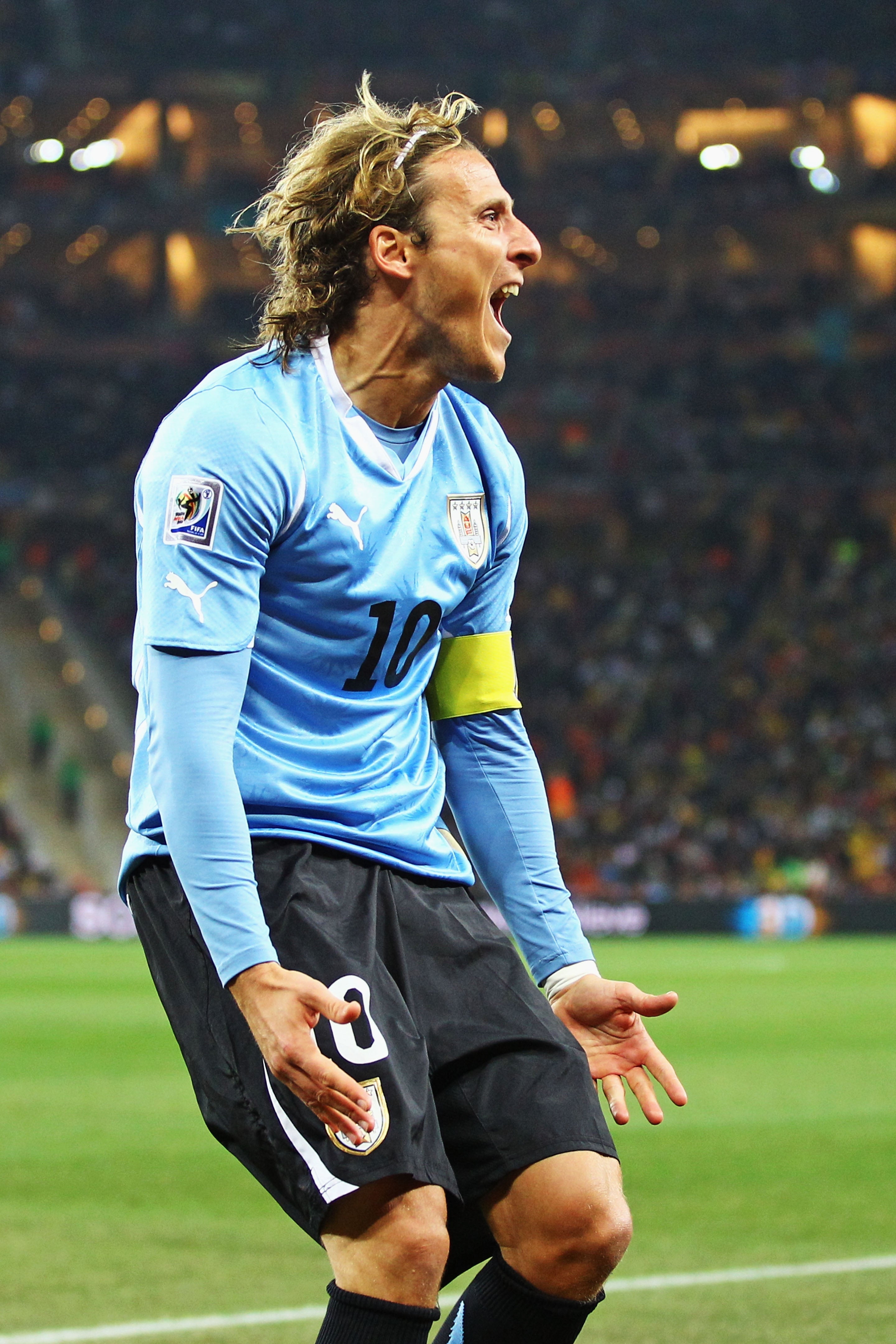 A shot subordinate successful a squad jersey celebrates passionately during a match, showing a yellowish captain's armband