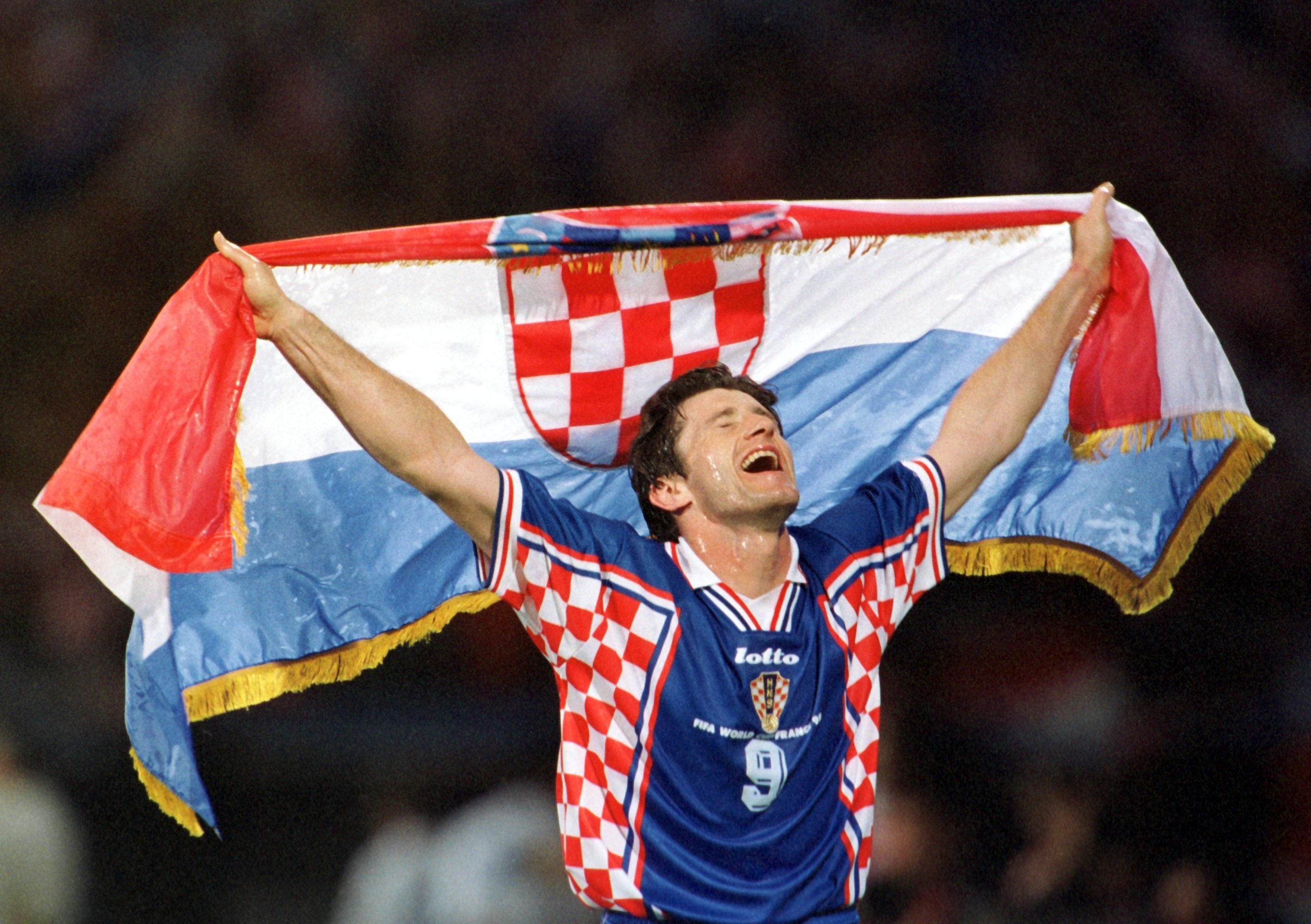Soccer subordinate celebrates connected the field, holding a Croatian emblem supra his head, wearing a checkered jersey