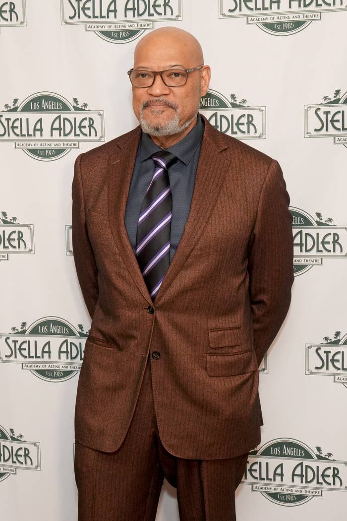 Man in a suit with a striped tie at an event backdrop labeled "Stella Adler."