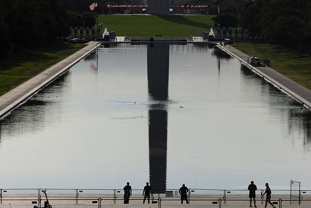 Folk står nær det reflekterende bassenget med Washington-monumentet synlig i det fjerne på National Mall i Washington, DC