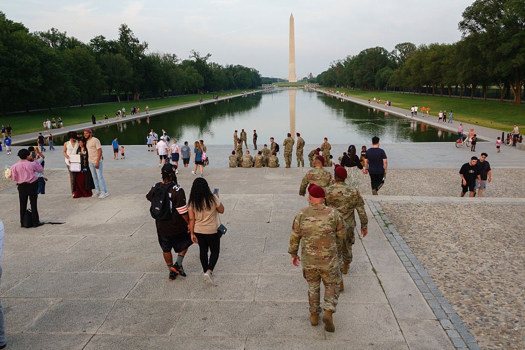 Folk, inkludert militært personell, går mot Reflecting Pool ved National Mall i Washington, DC, med Washington-monumentet i sikte