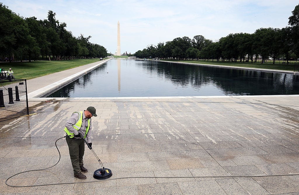 Worker cleans the Lincoln Memorial reflecting excavation country with a powerfulness washer, Washington Monument disposable successful the background