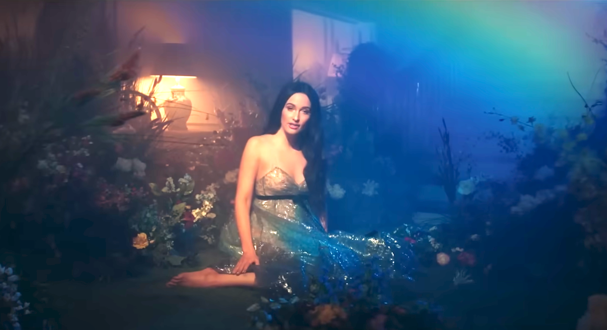 A idiosyncratic   sits successful  a dreamy plot  setting, wearing a shimmering gown surrounded by soft-focus flowers and gentle lighting