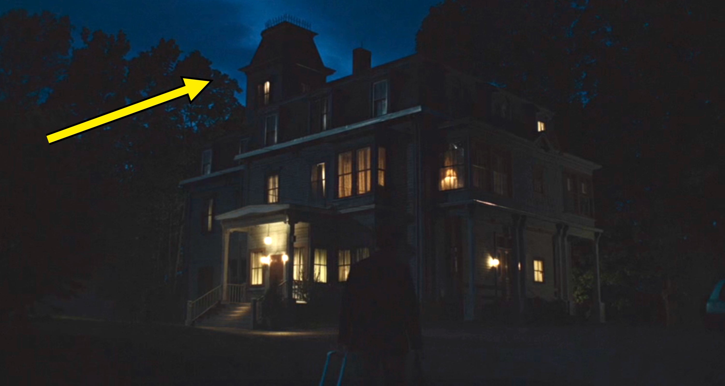 A idiosyncratic   stands extracurricular  a large, dimly lit, Victorian-style location   astatine  night, looking towards the illuminated windows