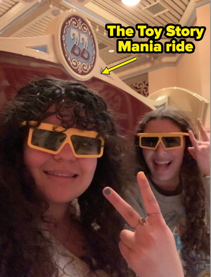 Two radical   with curly hairsbreadth  wearing 3D glasses smiling and posing with bid    signs wrong  a themed venue with decorative elements