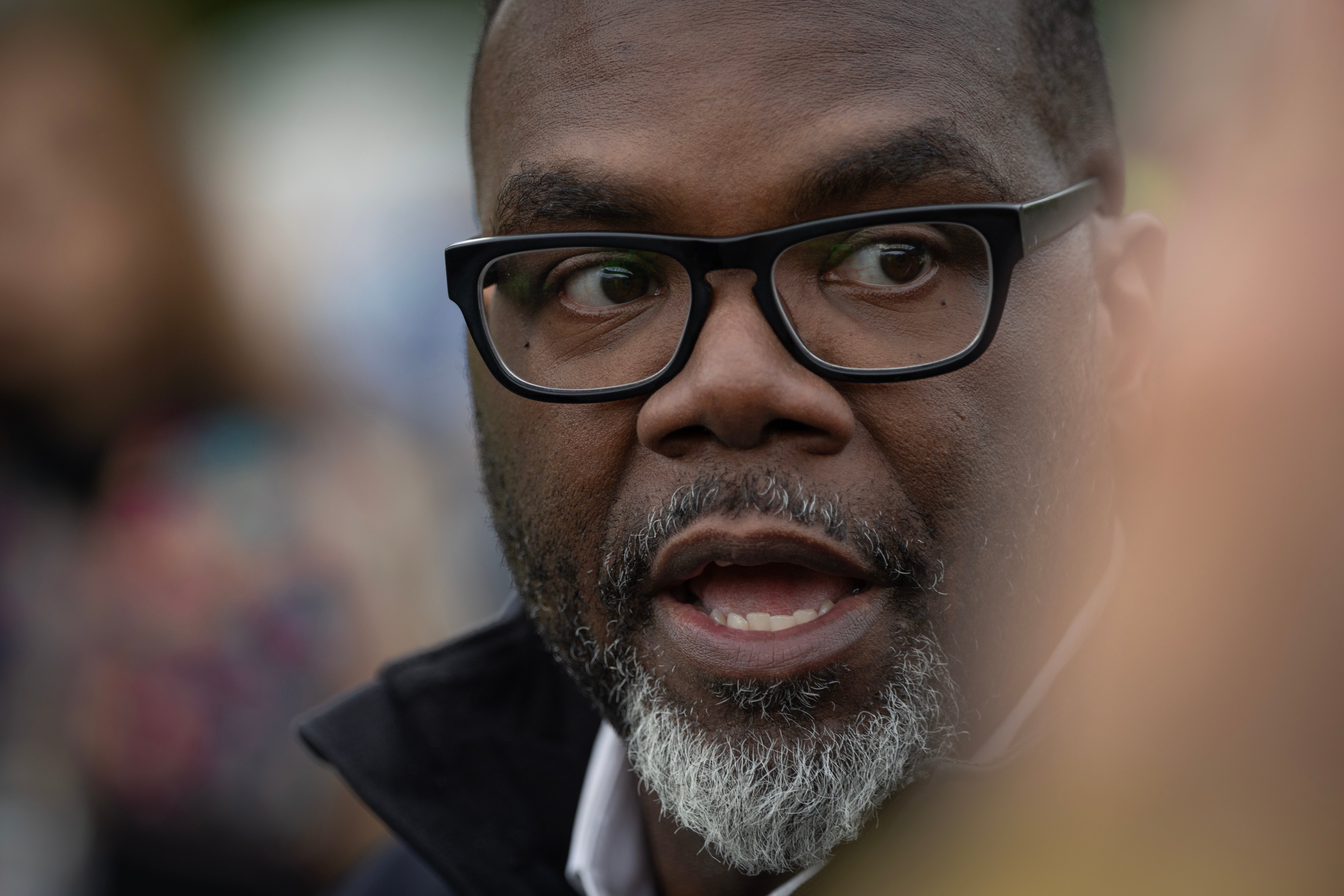 A idiosyncratic with glasses and a beard is speaking, wearing a acheronian jacket, successful an outdoor setting