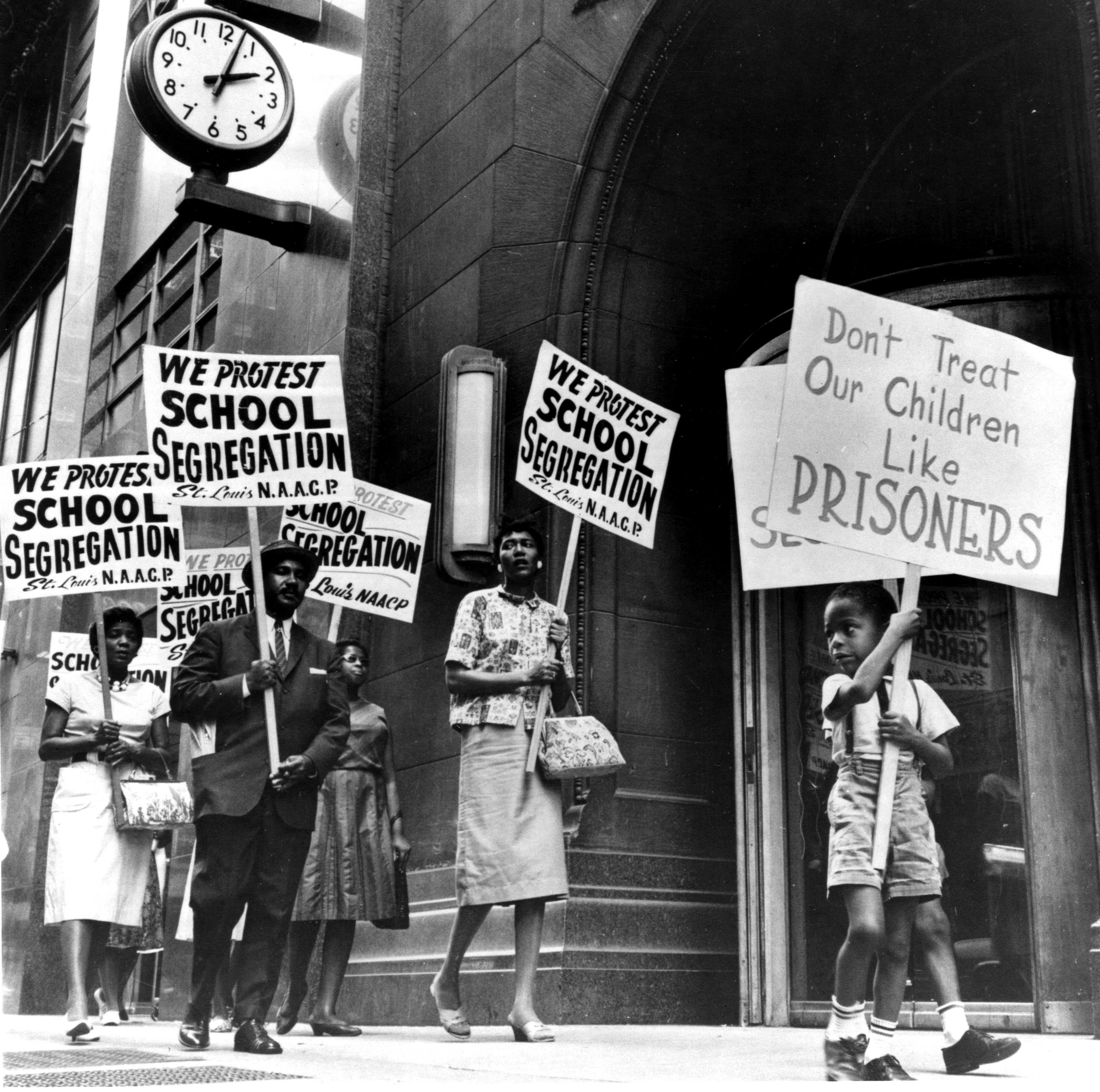 Protesters march against schoolhouse segregation. A young kid holds a motion speechmaking "Don't Treat Our Children Like Prisoners" extracurricular a building