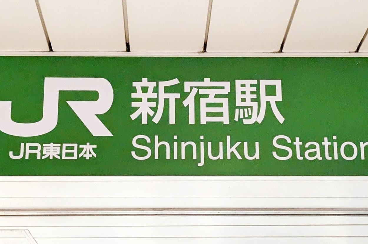新宿駅西改札口の看板が示すエントランス。駅利用者の一部が見える。