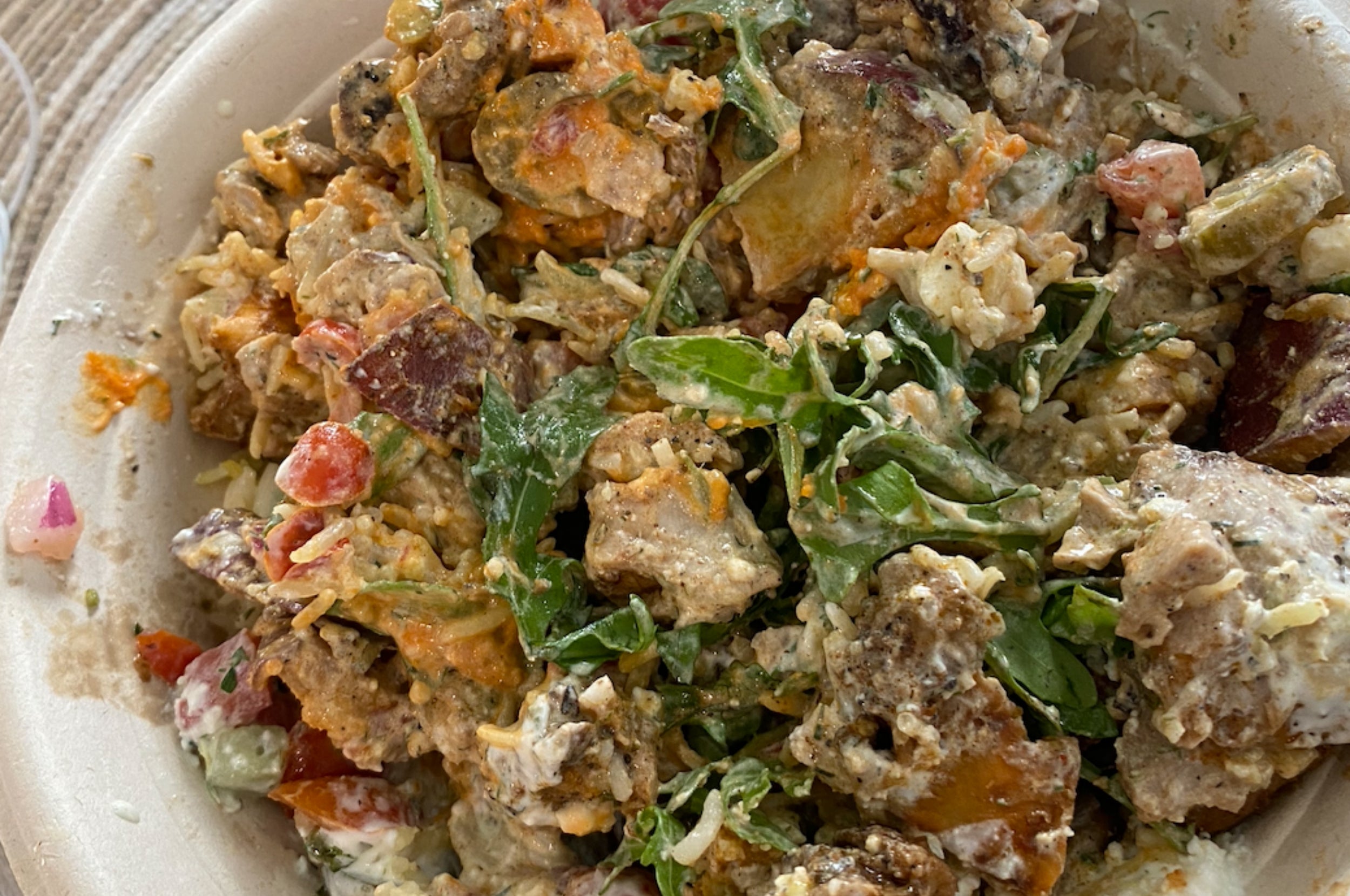 A vessel of mixed crockery with disposable greens, chopped vegetables, and crumbled feta cheese