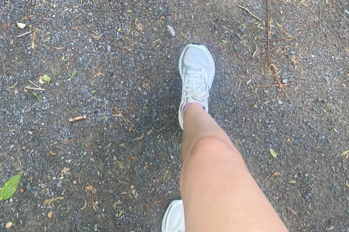 Person walking connected  a gravel path, wearing achromatic  sneakers