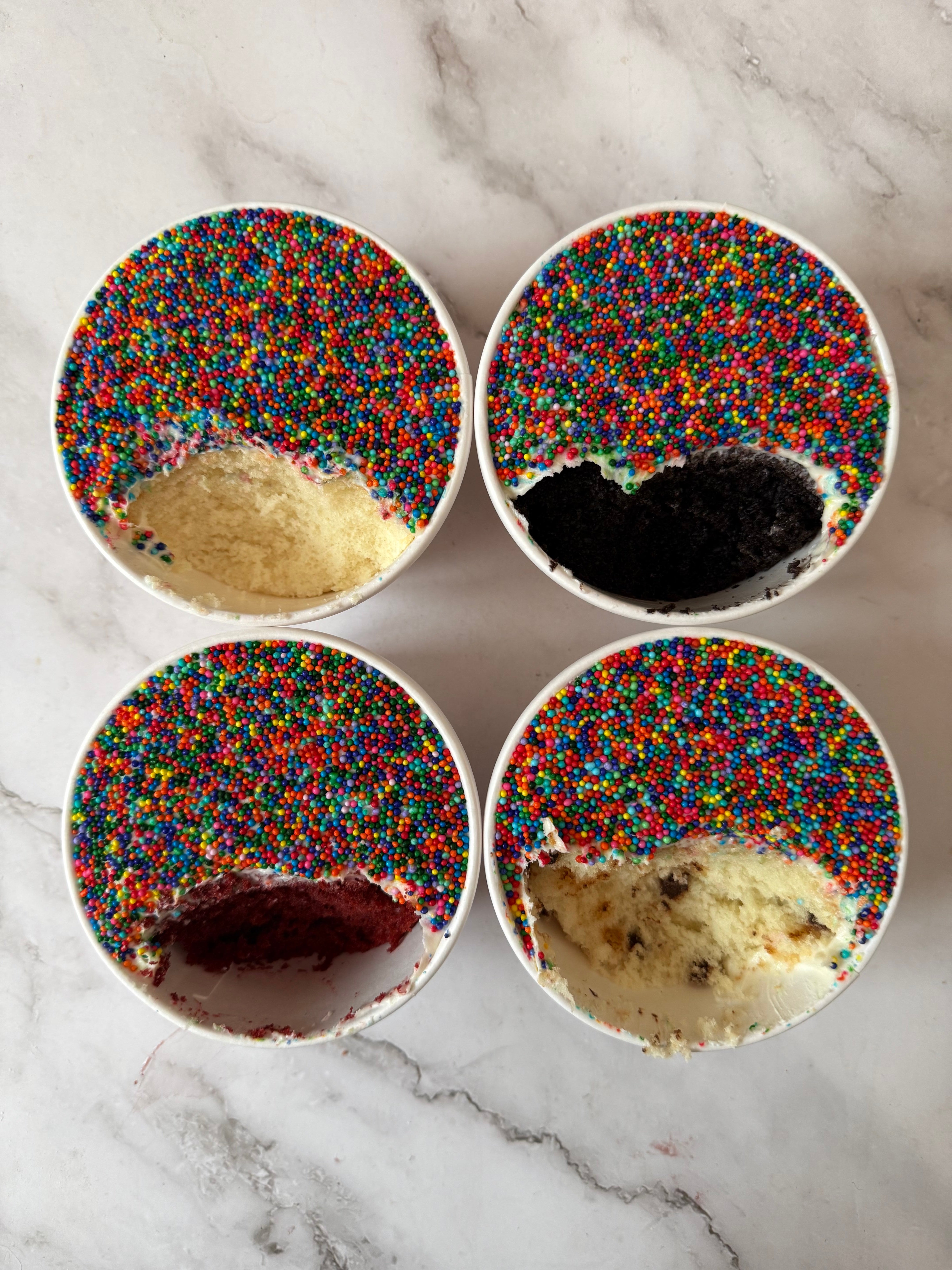 Four bowls of cake, each   topped with colorful sprinkles. The bowls person  antithetic  flavors disposable   beneath   the sprinkles