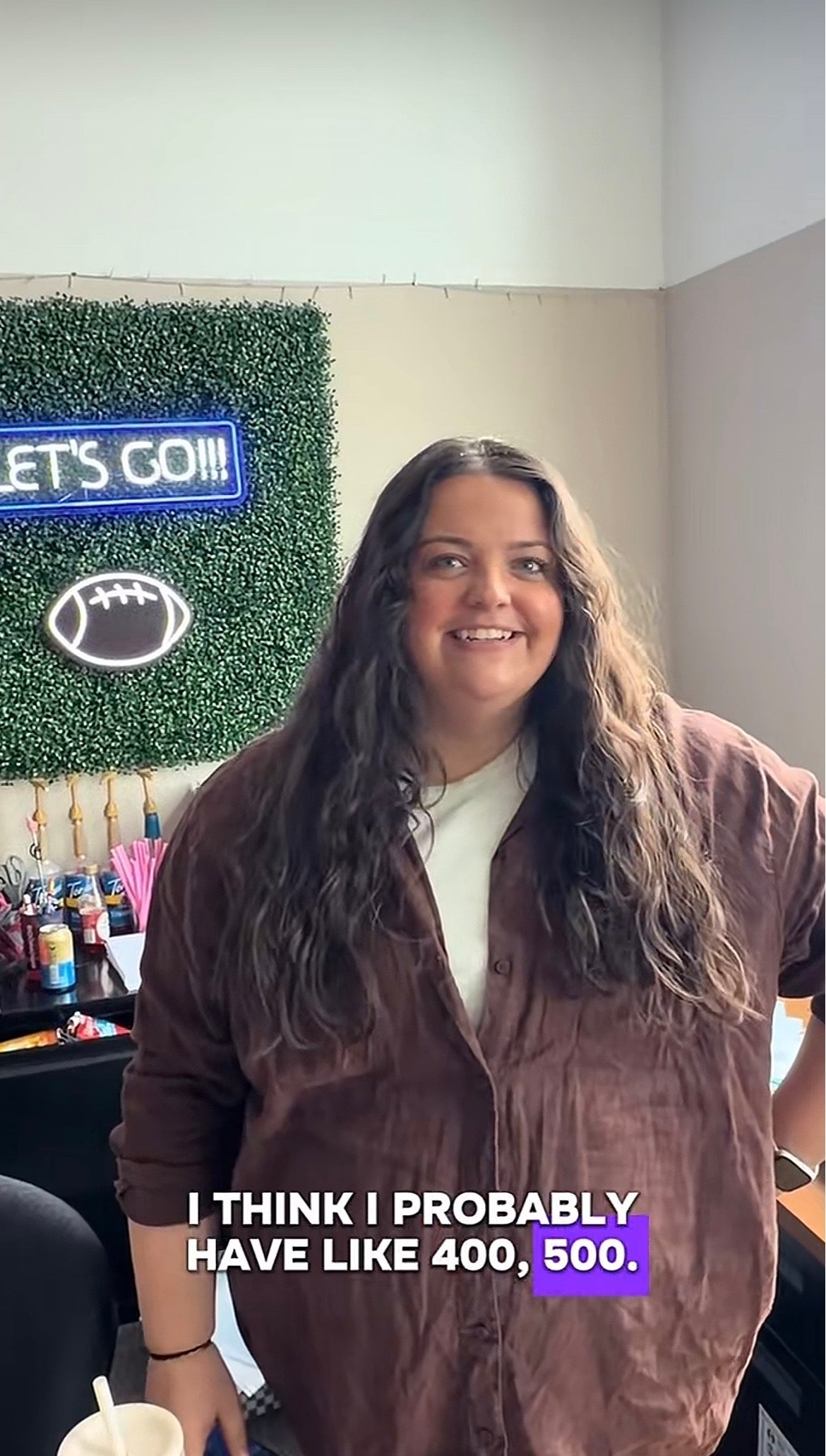 Person smiling successful  an bureau   setting, wearing a casual shirt. Neon motion   successful  the inheritance  says "LET'S GO!!!"