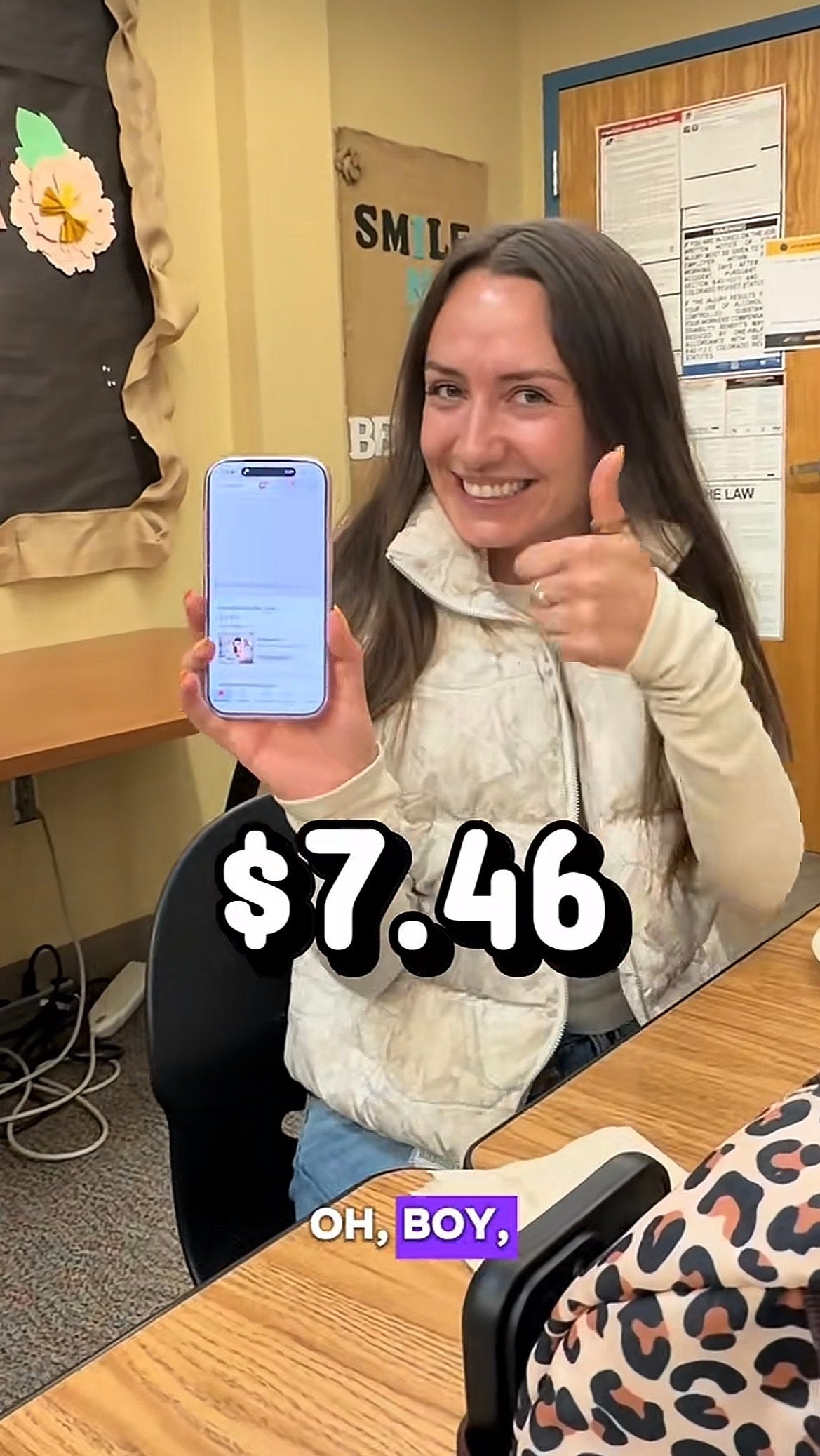 Person successful  a schoolroom  gives a thumbs-up portion    holding a telephone  displaying a outgo   of $7.46