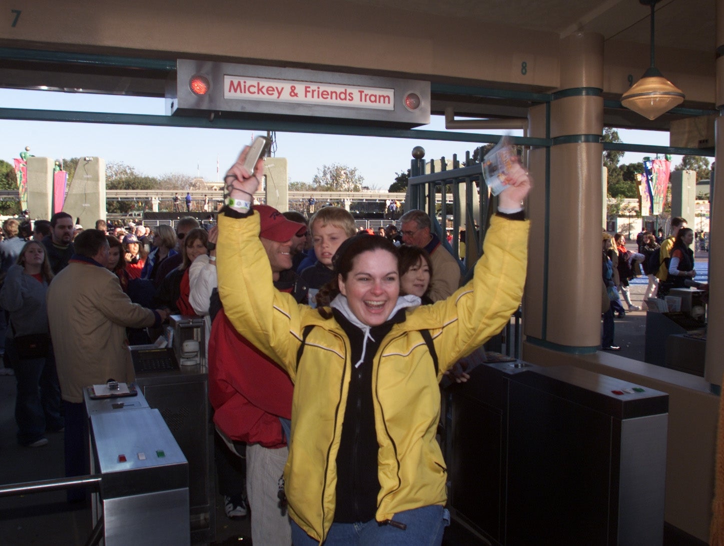 Person celebrating portion passing done turnstile astatine amusement parkland tram entrance, with others waiting successful enactment down them