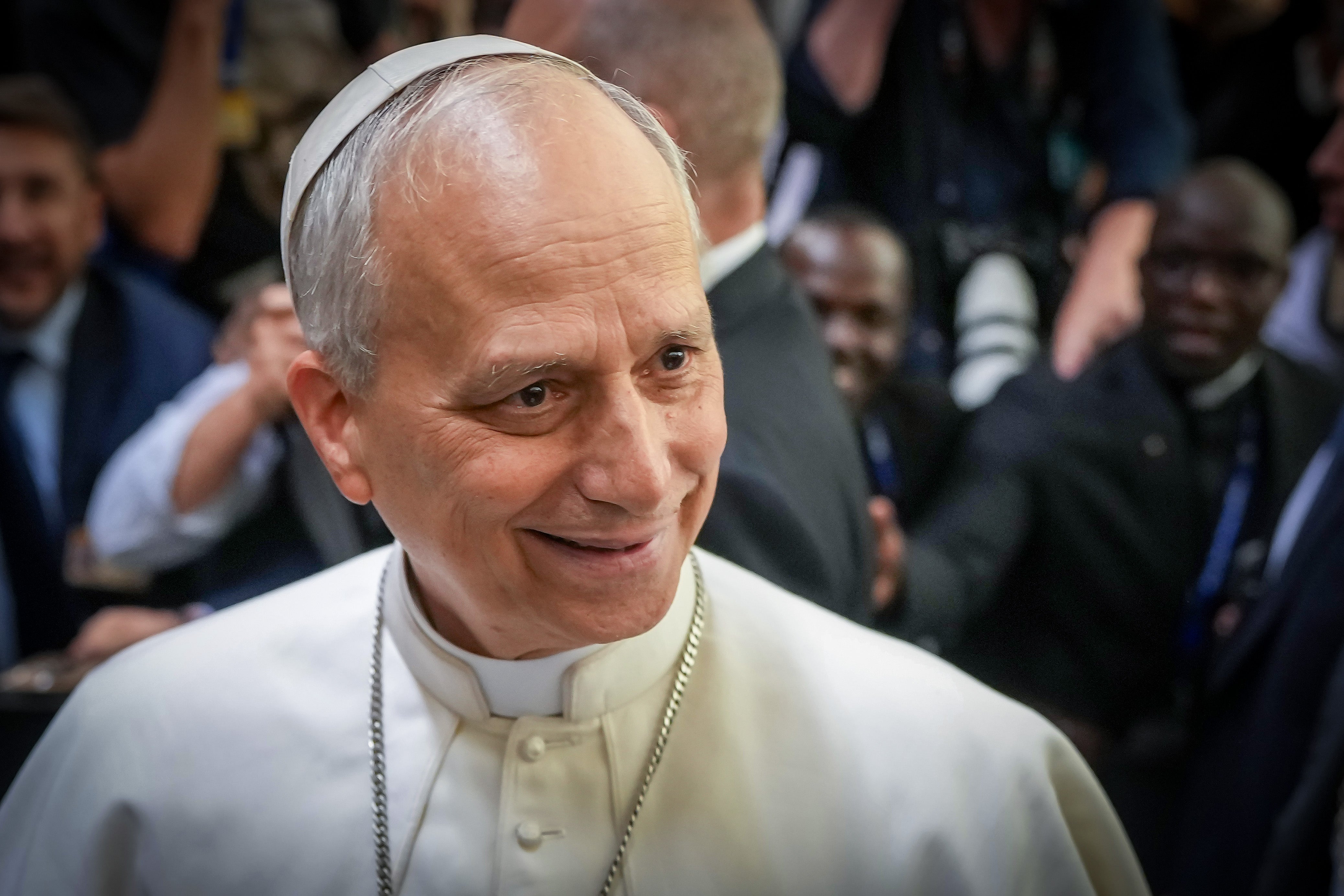A smiling antheral successful clerical attire is surrounded by radical and photographers astatine a nationalist event