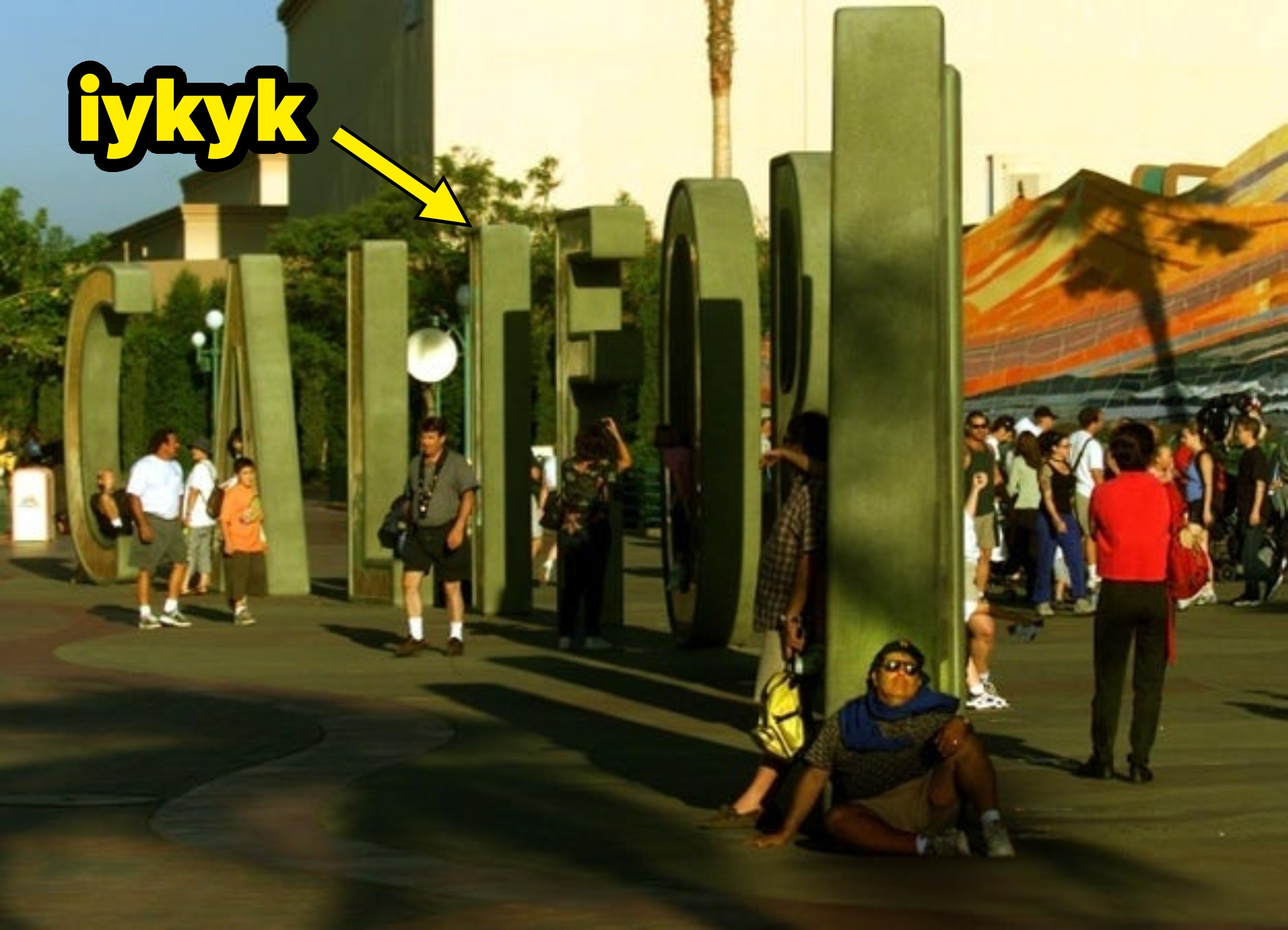 People walking astir large, sculpted letters spelling "California" successful an outdoor plaza. One idiosyncratic is sitting and resting successful the shade