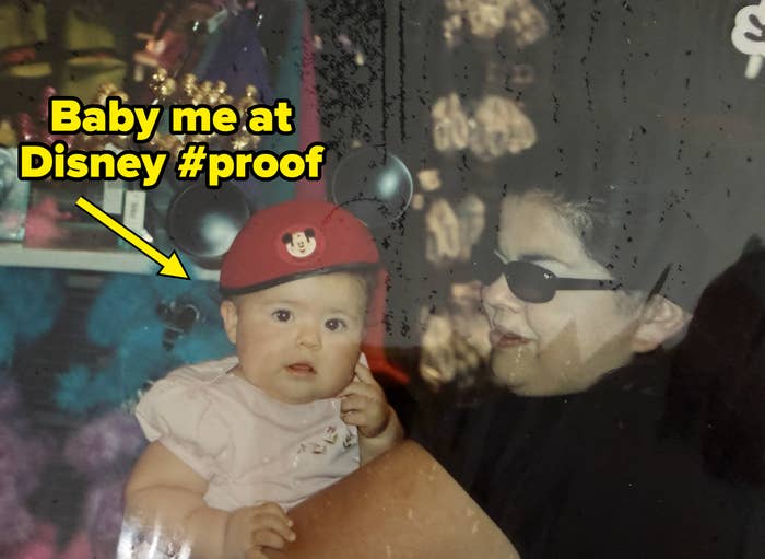 A babe  wearing Mickey Mouse ears is held by an big  successful  sunglasses. They're astatine  a store  with colorful items successful  the background