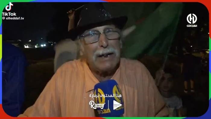 An aged  antheral   speaks into a microphone during an outdoor nighttime  event, perchance  an interrogation  oregon  celebration