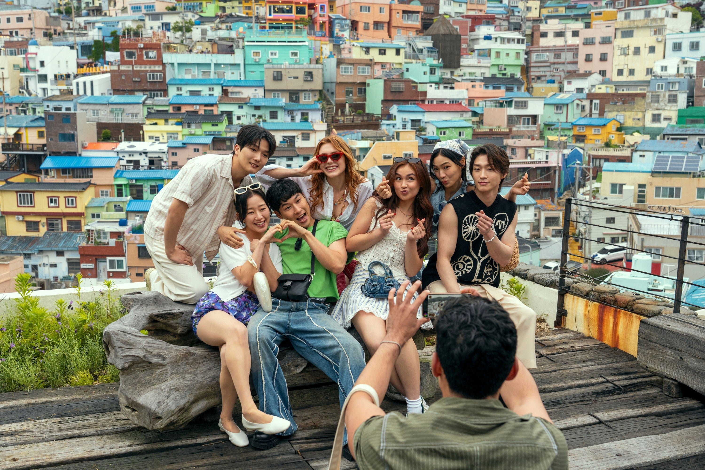 A group of people posing playfully on a wooden platform with colorful houses in the background