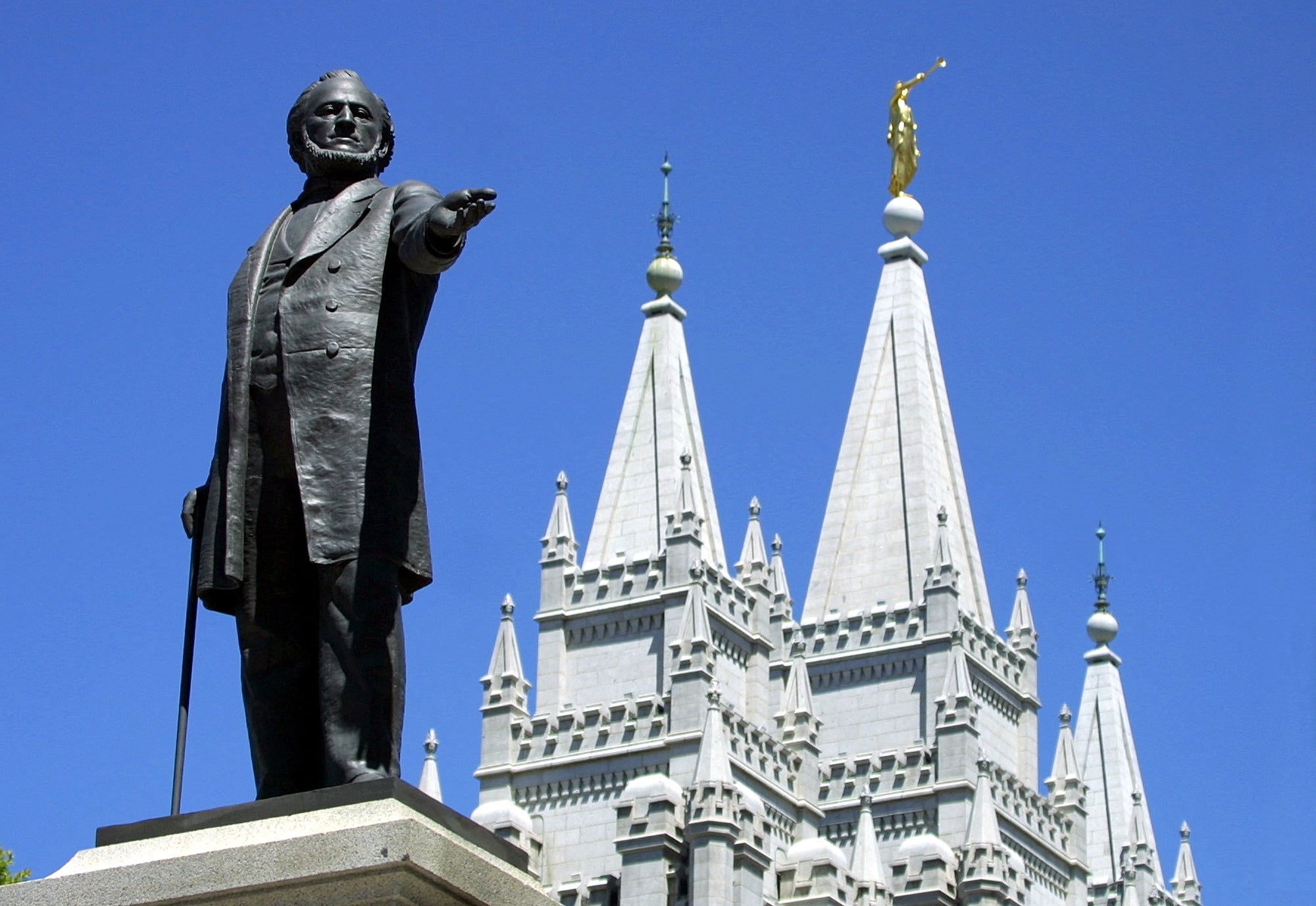 A statue of a lasting fig with an outstretched arm, positioned successful beforehand of a historic, pointed architectural operation with a aureate statue