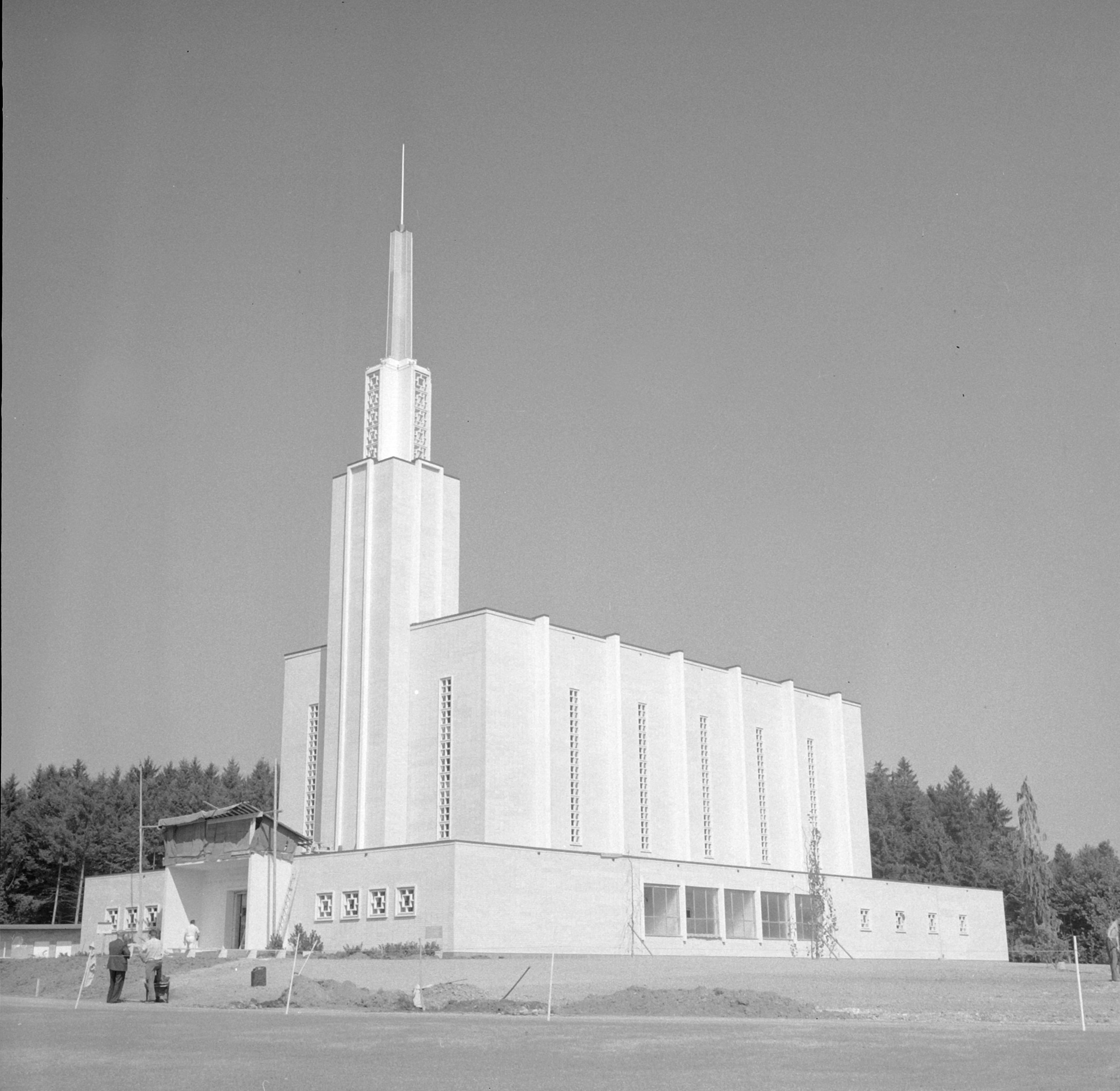 A tall, modern gathering with geometric plan elements, surrounded by trees. A fewer radical are adjacent the entrance