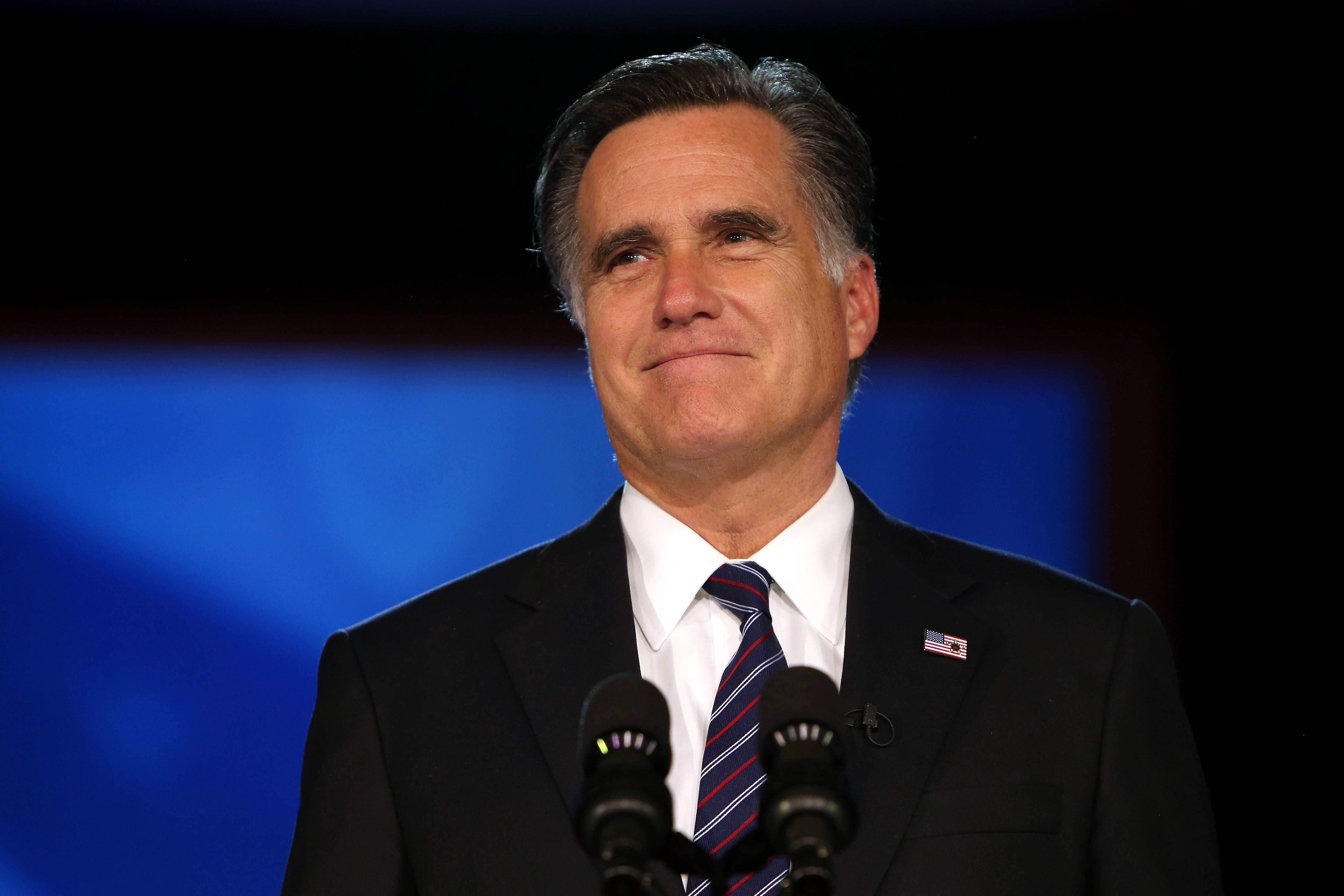 A idiosyncratic successful a suit stands astatine a podium with microphones, appearing thoughtful during a nationalist speaking event