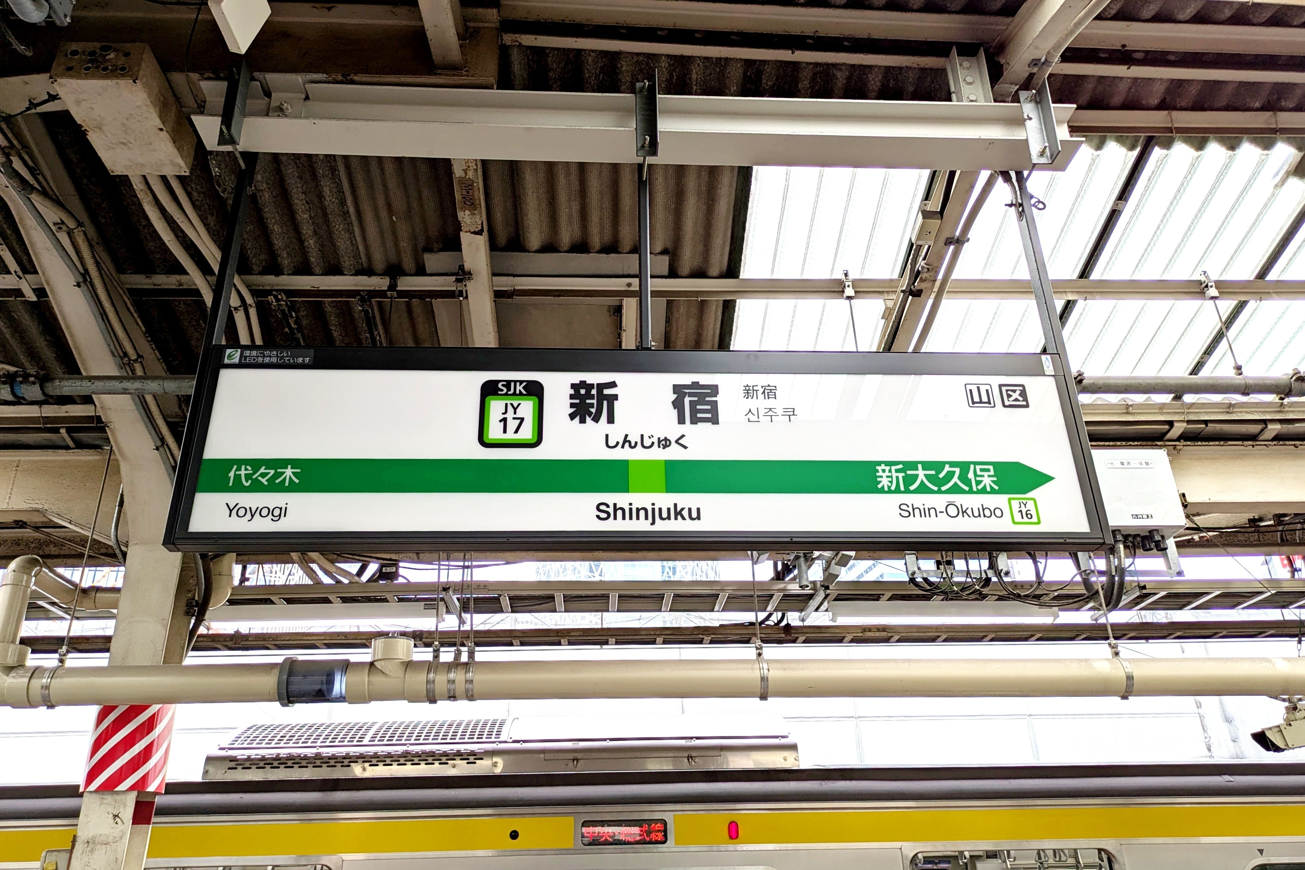 新宿駅のプラットフォームにある駅名標。代々木と新大久保が近隣駅として示されている。