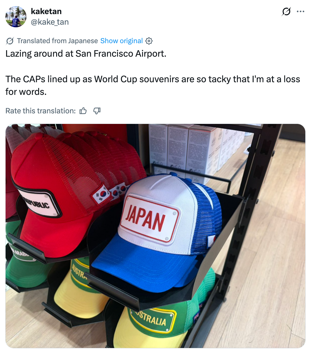 Display of colorful World Cup souvenir caps with state  names similar  Japan and Australia astatine  San Francisco Airport. Text critiques their tackiness