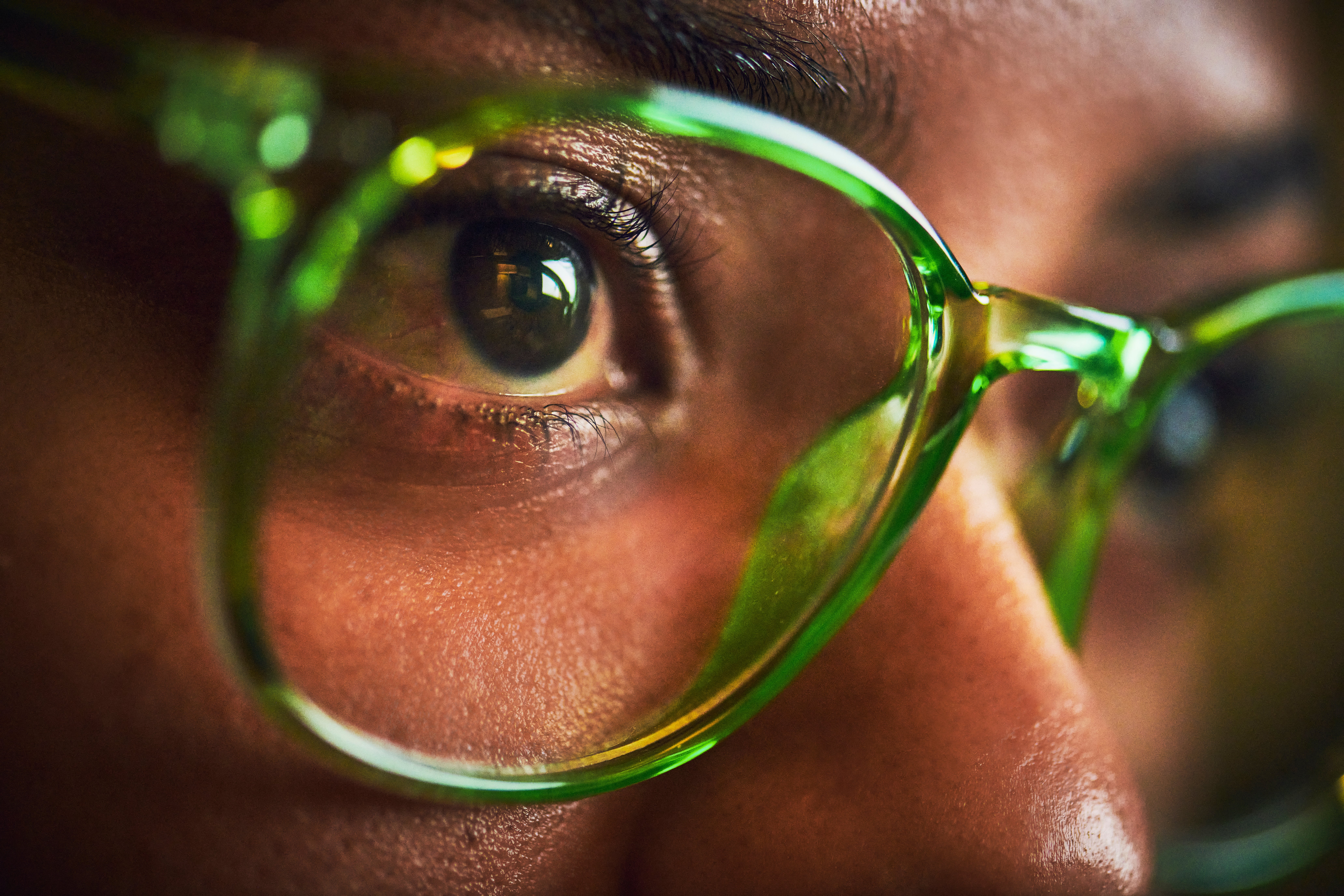Close-up of a person's eyes, wearing large, translucent glasses with a reflective surface