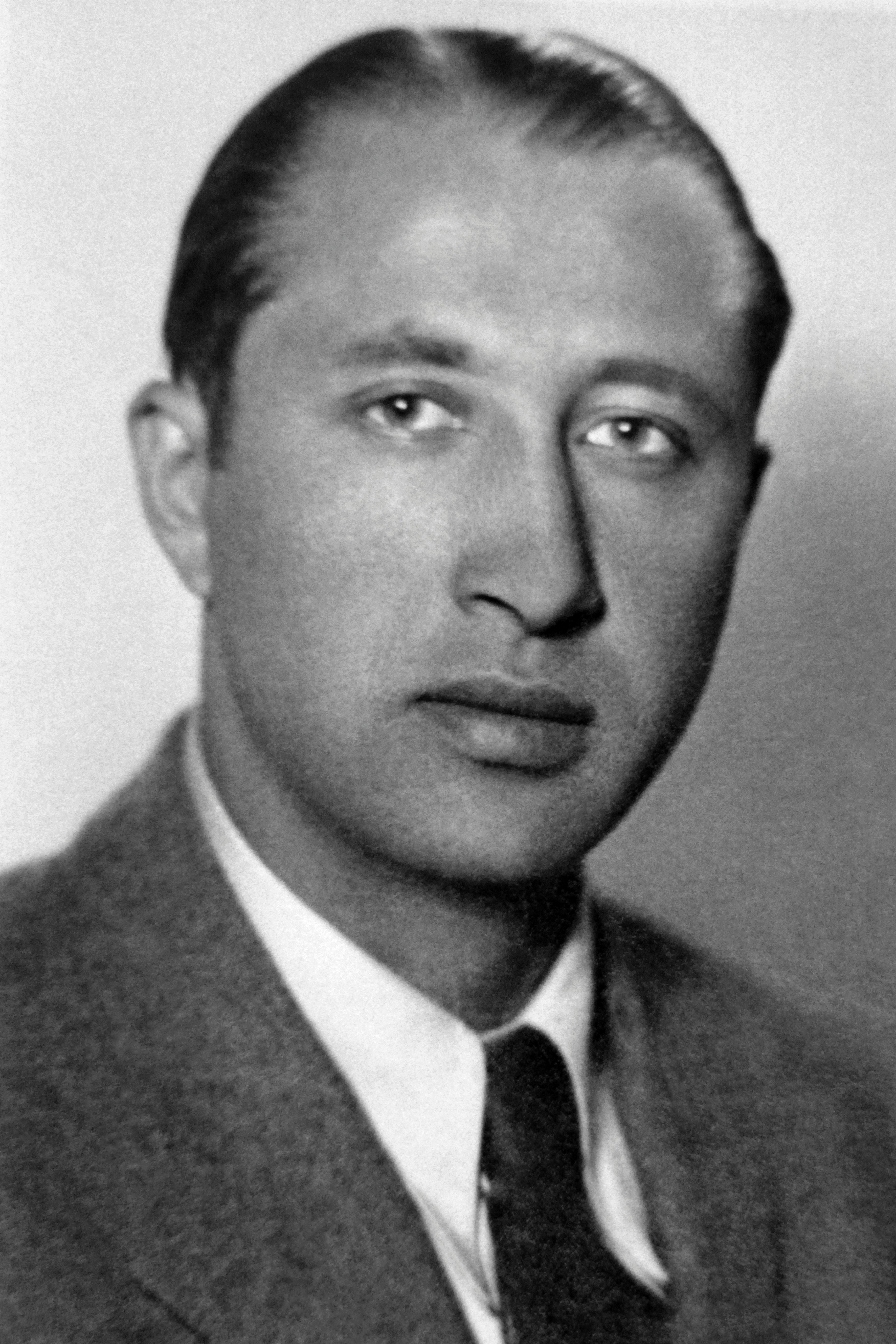 Man successful  a suit   and tie, with a superior   expression, looking straight  astatine  the camera