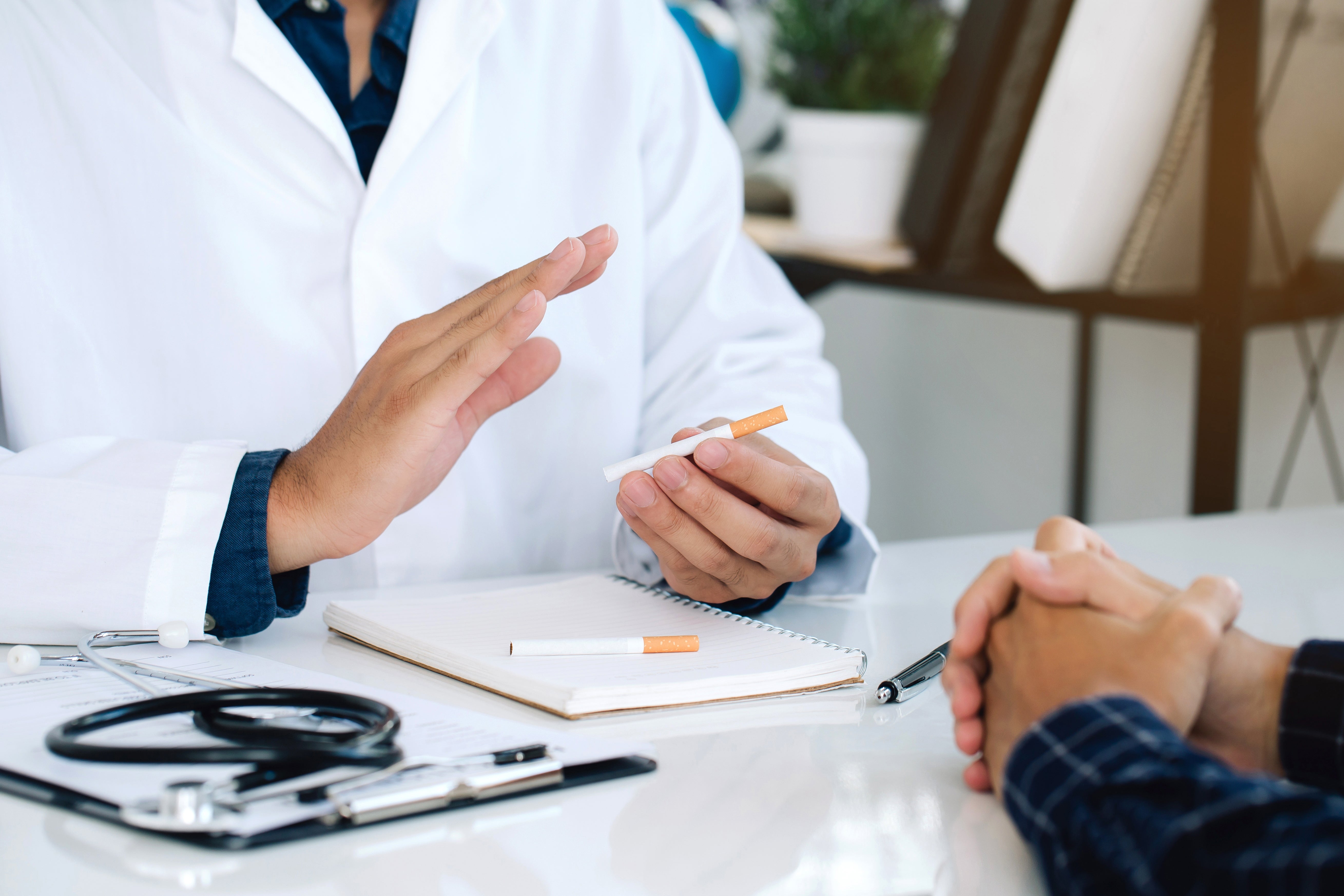 Doctor discusses smoking cessation with a patient, utilizing a cigaret arsenic a prop astatine a aesculapian table setting