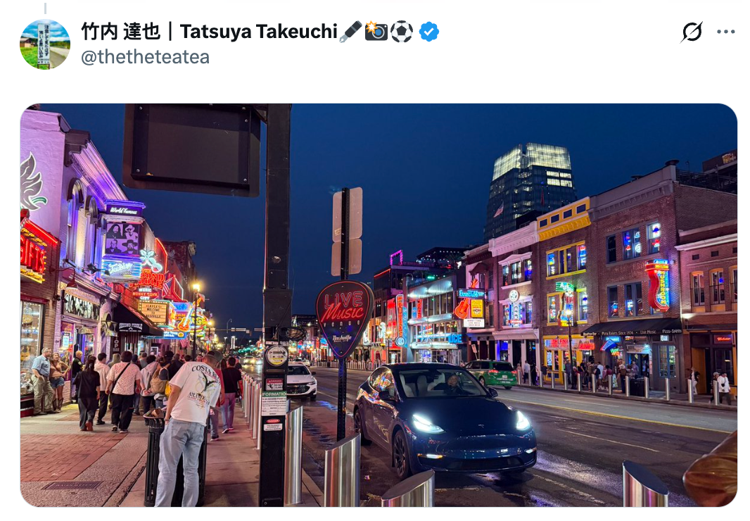 City thoroughfare  astatine  nighttime  with vibrant lights and radical   extracurricular  bars and restaurants; a car   is parked connected  the road