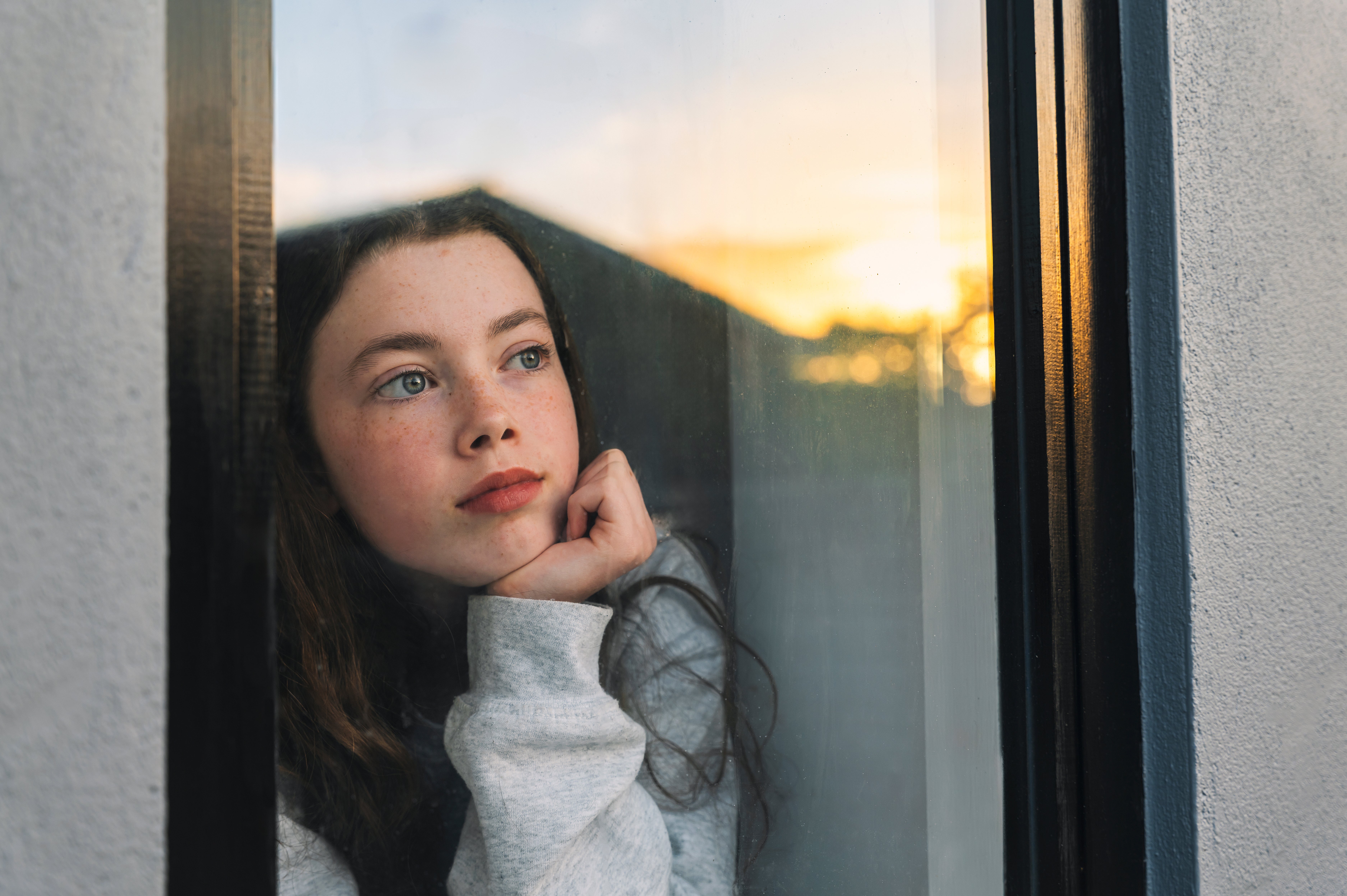 Person gazes thoughtfully retired a model astatine sunset, wearing a casual sweatshirt